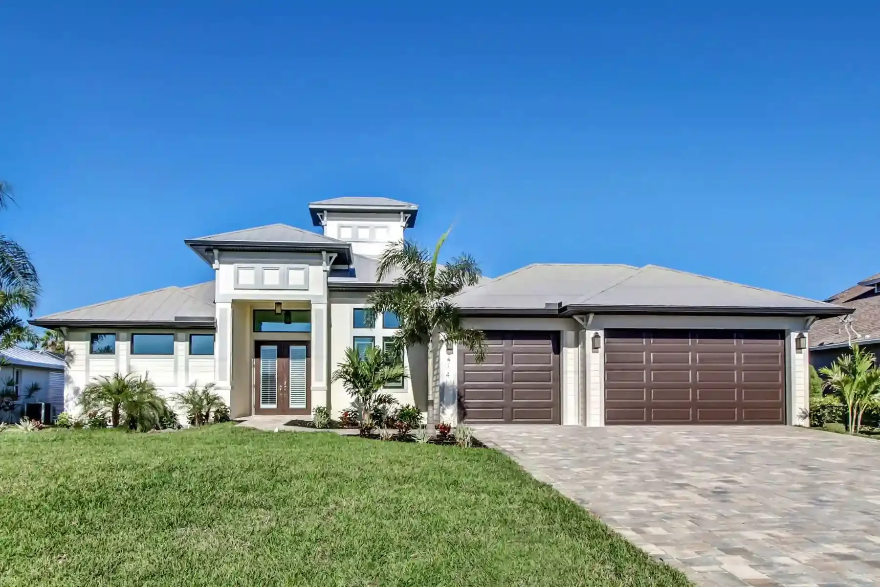 Gorgeous exterior of another custom built home from Sposen Signature Homes in Florida, landscaped with palm trees, 3 car garage, grand 2 story foryer, and up to 100% financing from BuildBuyRefi Home Loans.