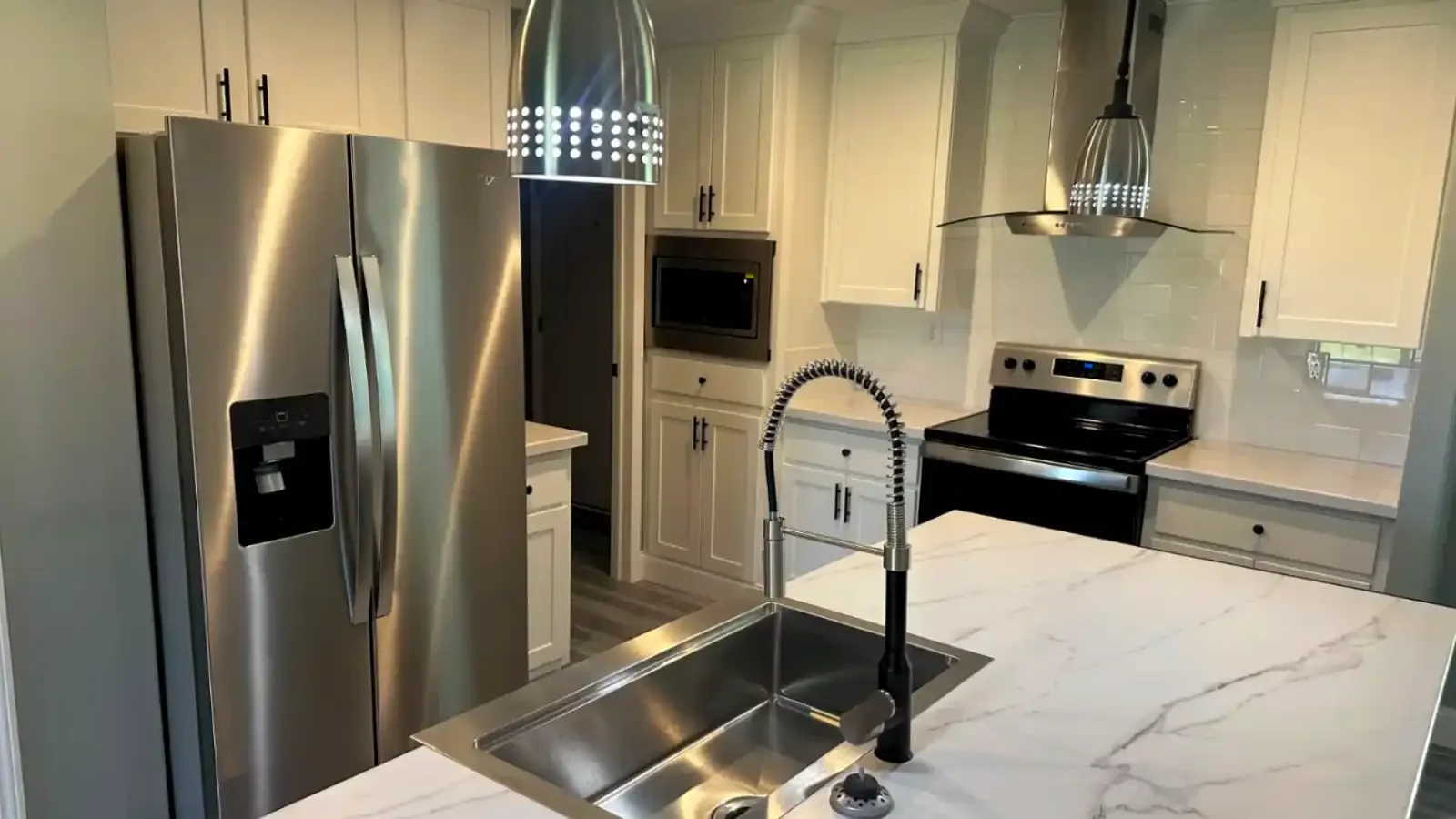 Upgraded Kitchen with Marble Counters, deep sink in center island, stainless appliances, pendant lights, full wall backsplash, in wall oven by Suncrest Homes of Florida and BuildBuyRefi Home Loans.