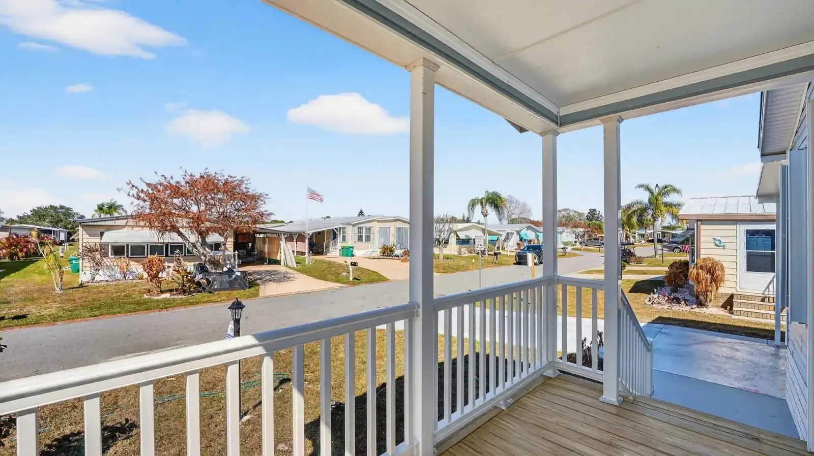Brand New Florida Value Homes doublewide, standing under the Covered Front Porch View looking out over a south florida manufactured home community, on a land and home loan package by BuildBuyRefi.com
