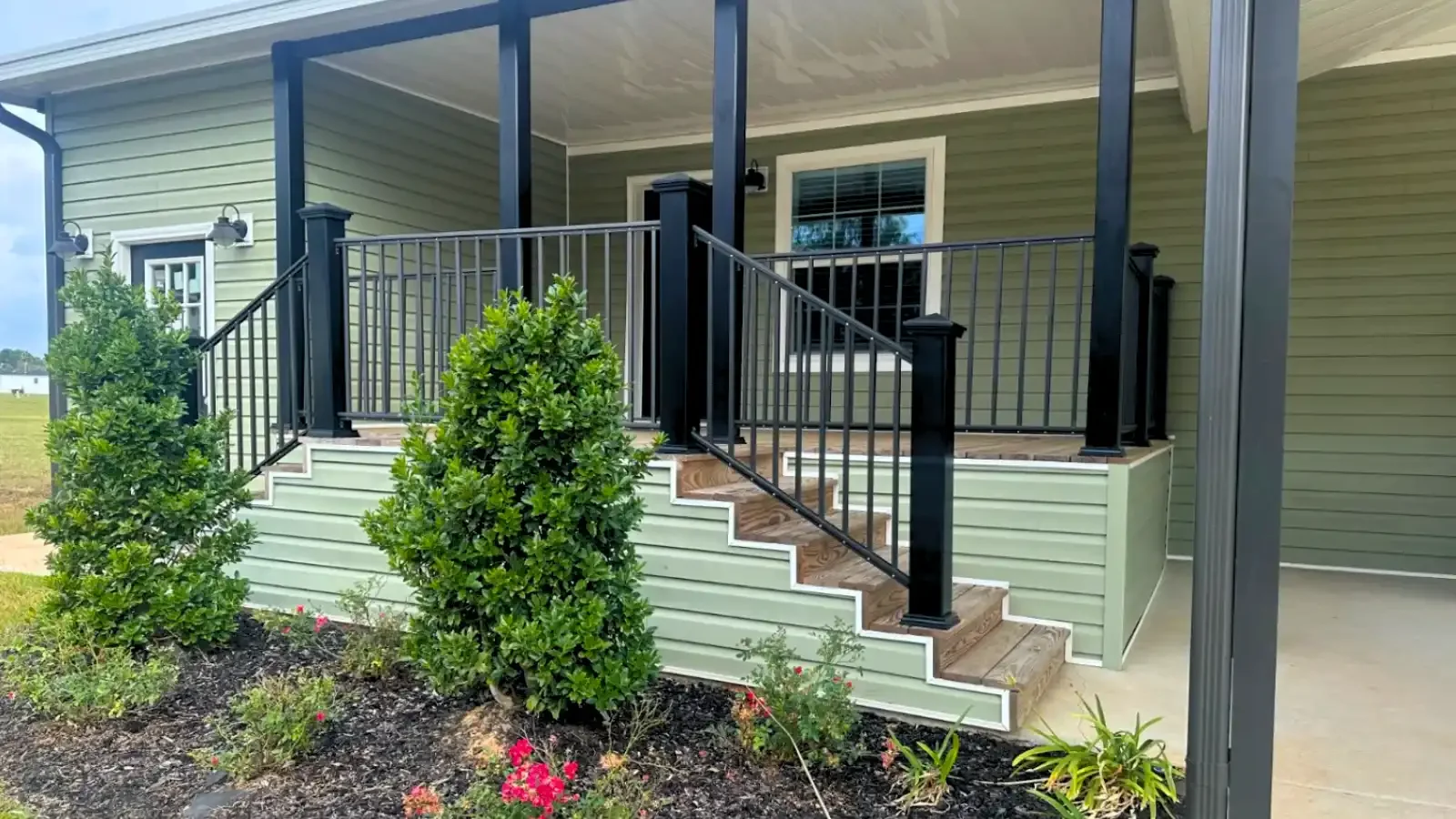Unique double stair front porch, two ways to enter the home, custom decking and pillars, and custom landscaping on a Florida style manufactured home by Suncrest Homes of Florida & BuildBuyRefi.com