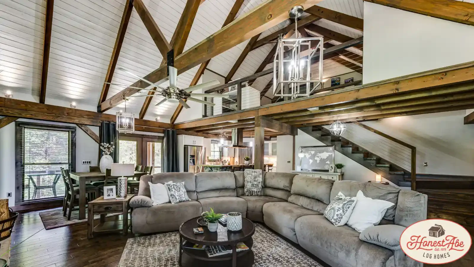 Gorgeous 2 Story Vaulted Timber Frame Great Room opening into the Kitchen and outside deck, custom lighting, stairways, and design excellence by Honest Abe Log Homes and BuildBuyRefi.com construction loans.