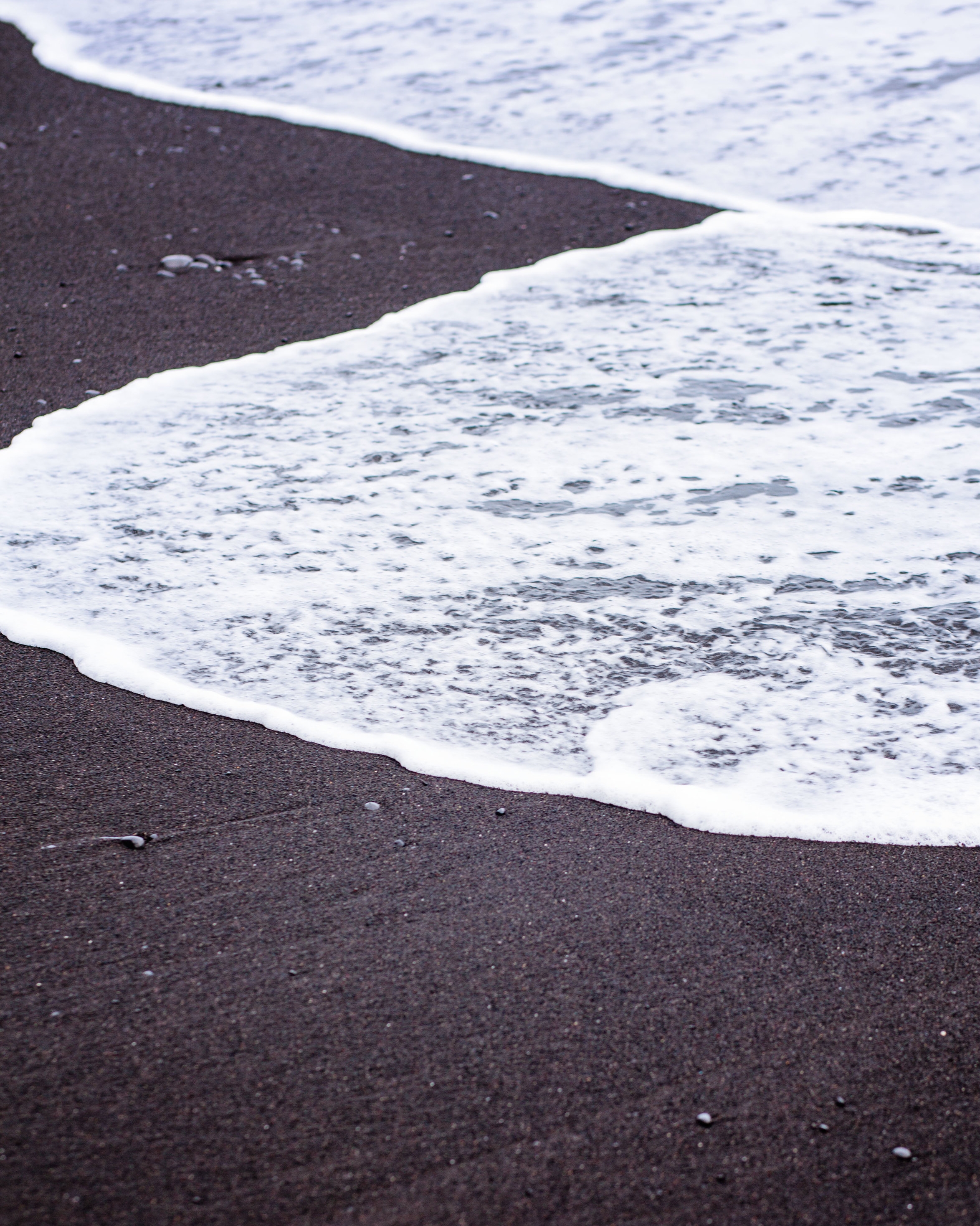 White sea foam on black sand