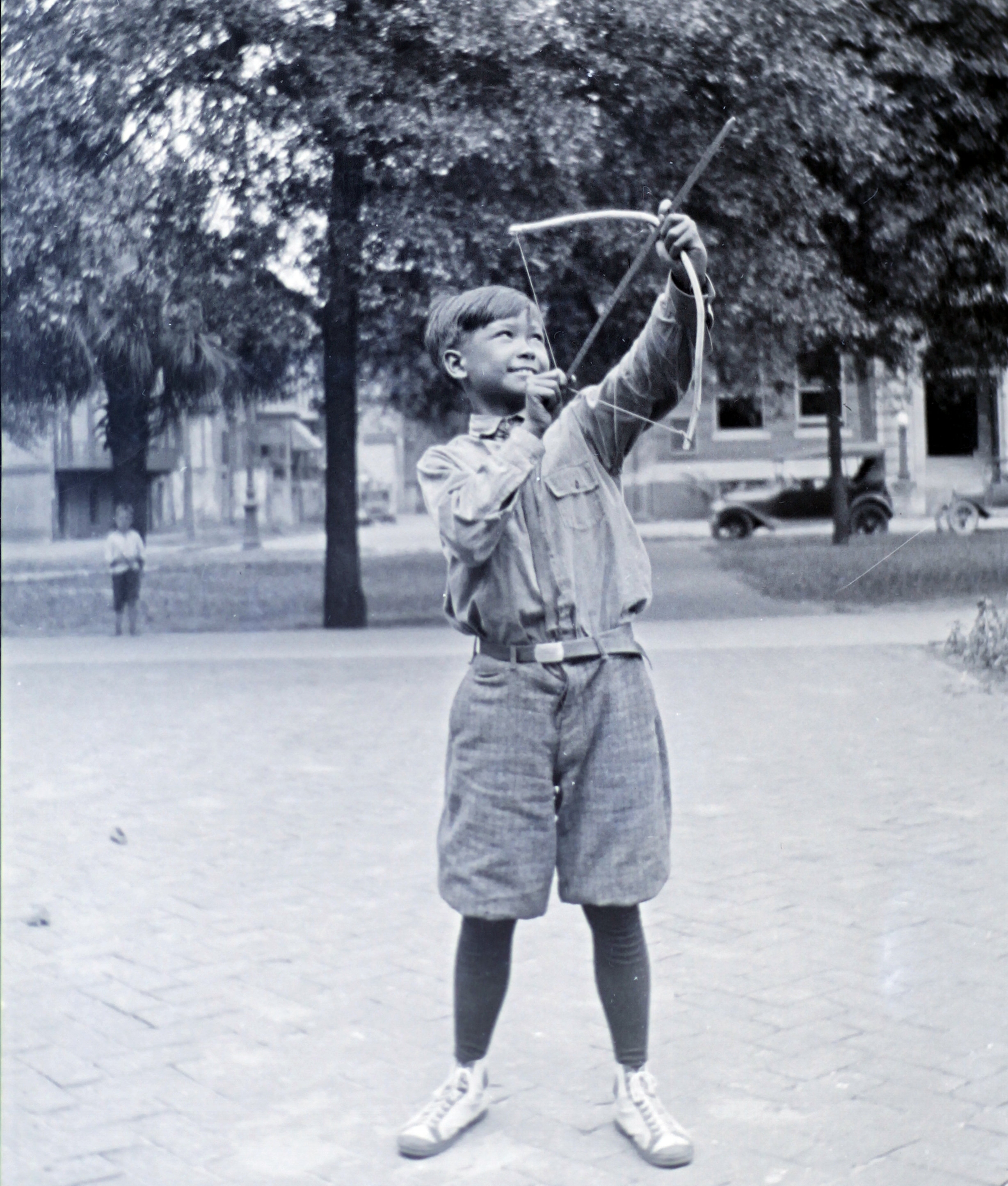 Playing Robin Hood in the park in his "short pants" that he loathed, a pair of Chuck Taylors, and with a handmade bow and arrow, ca. 1920