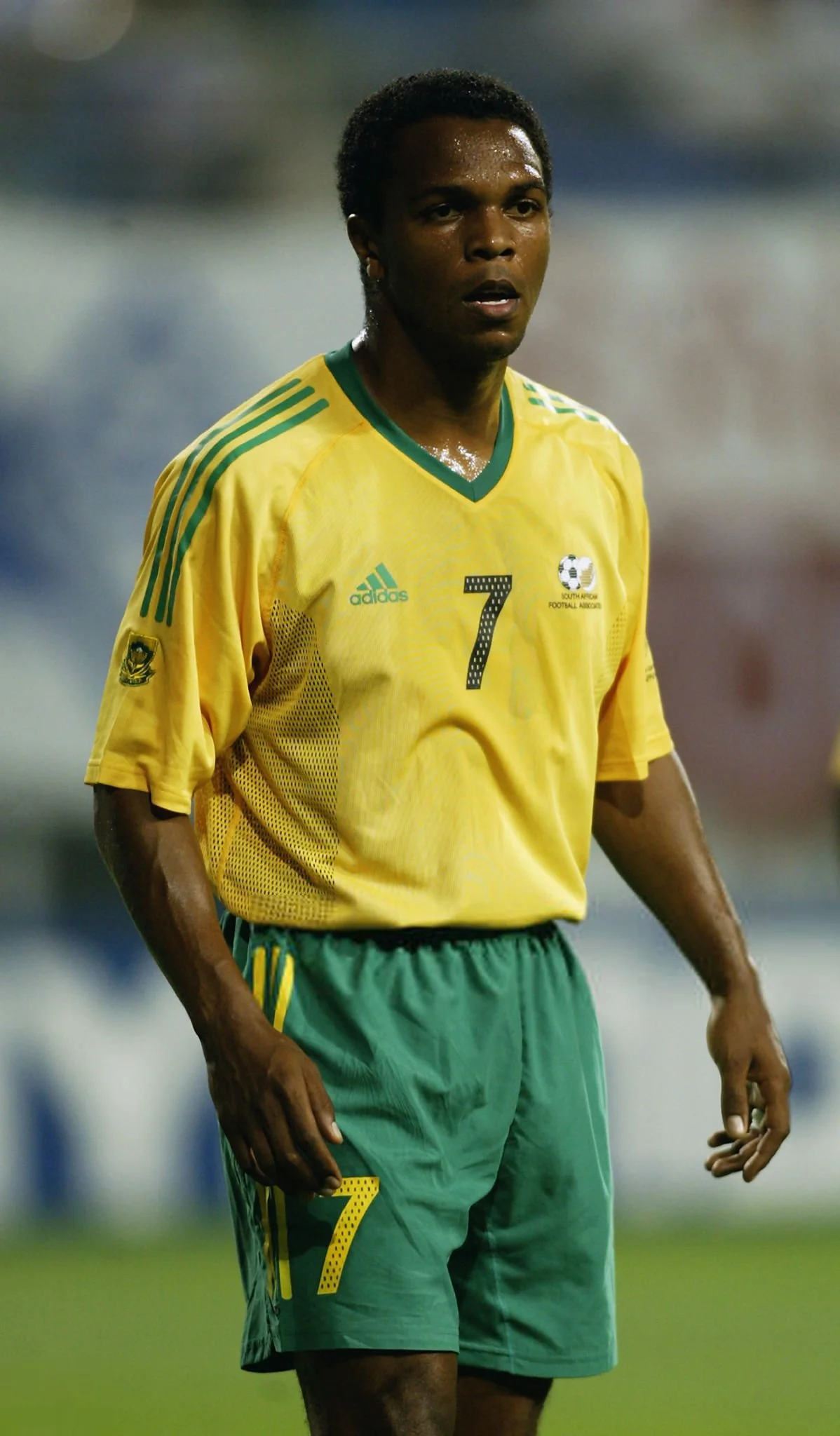 A soccer player wearing a yellow South Africa national team jersey with the number 7, standing on the field during a game.
