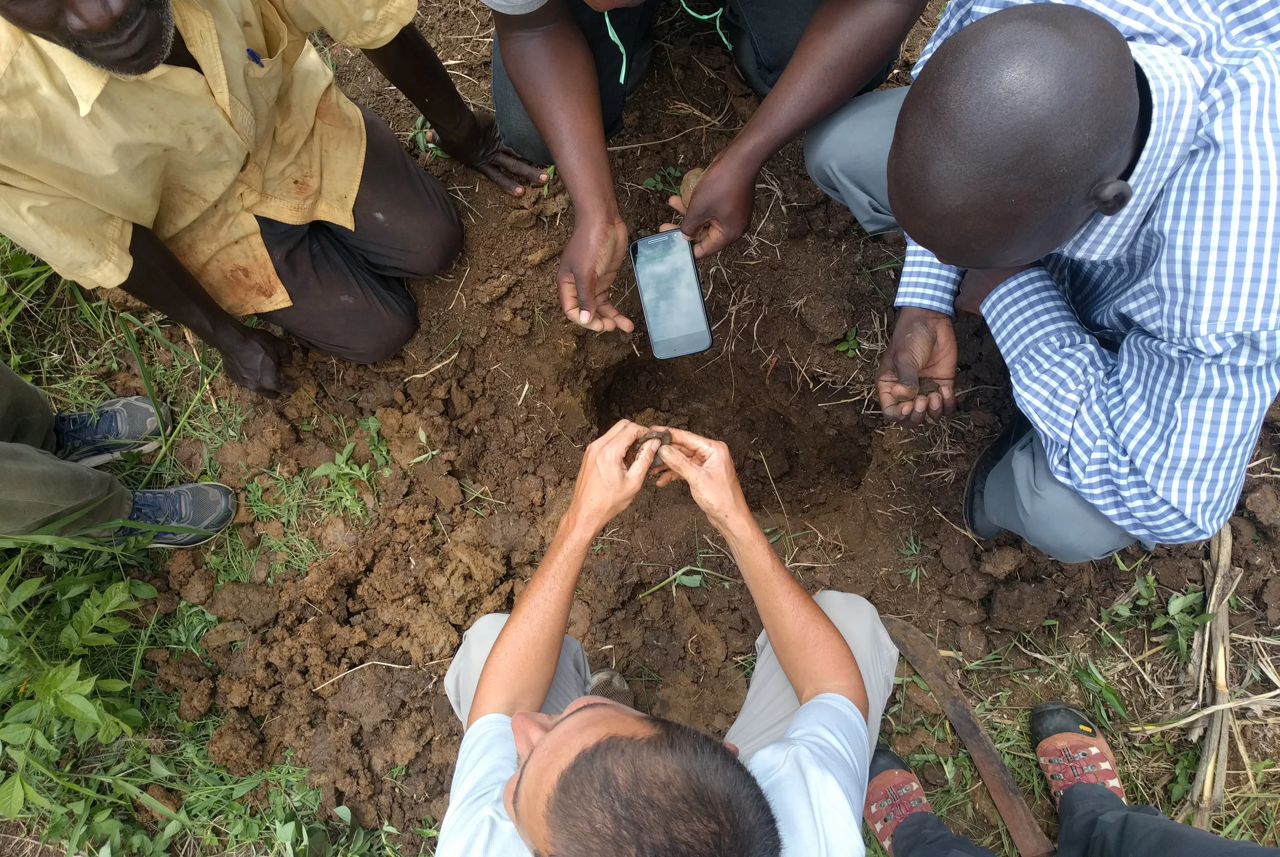 HIP team members exploring soil characterization with farmers at Kyekidde using a smartphone-based analysis app