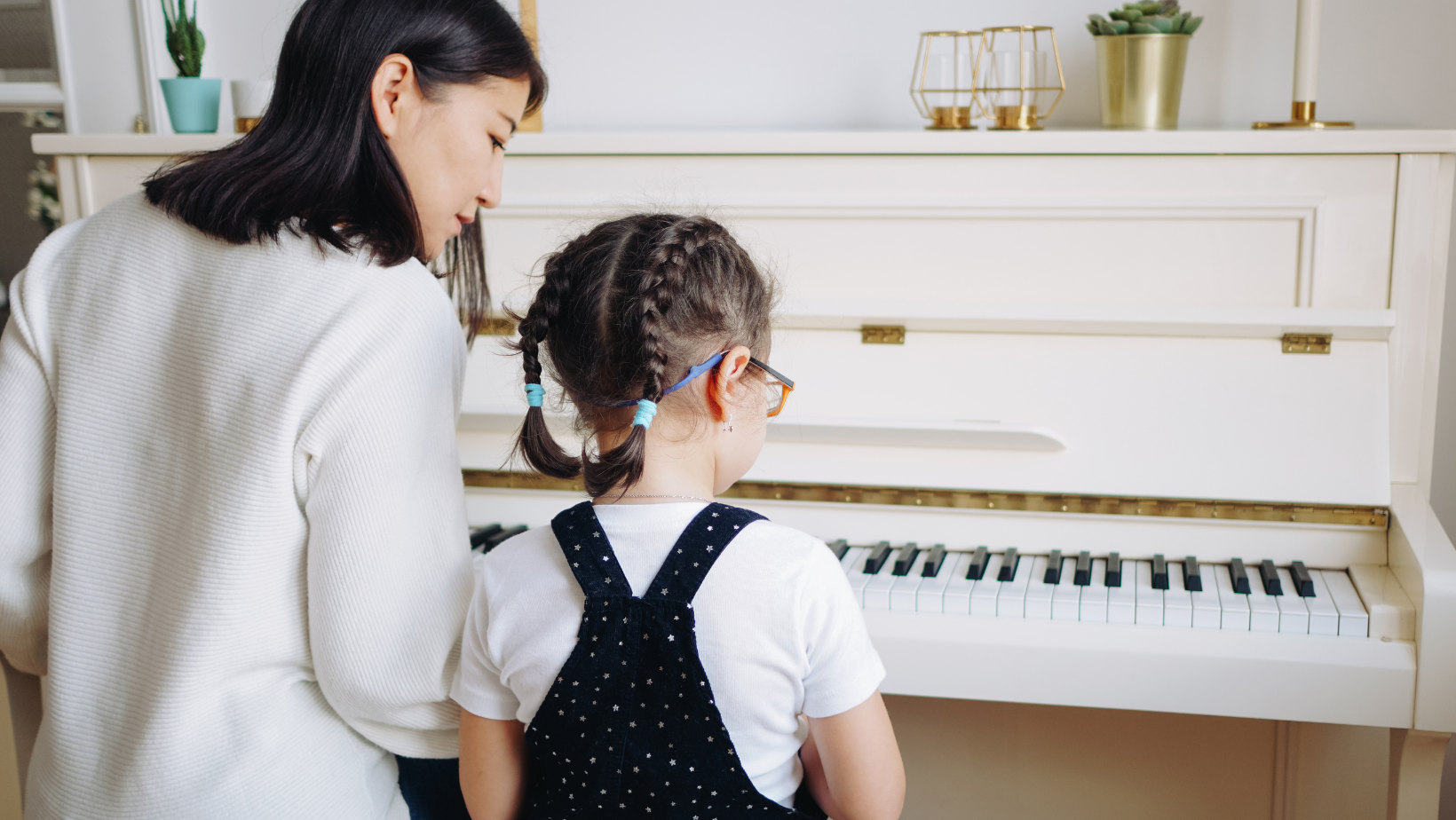 Music teacher supporting a young student at the piano