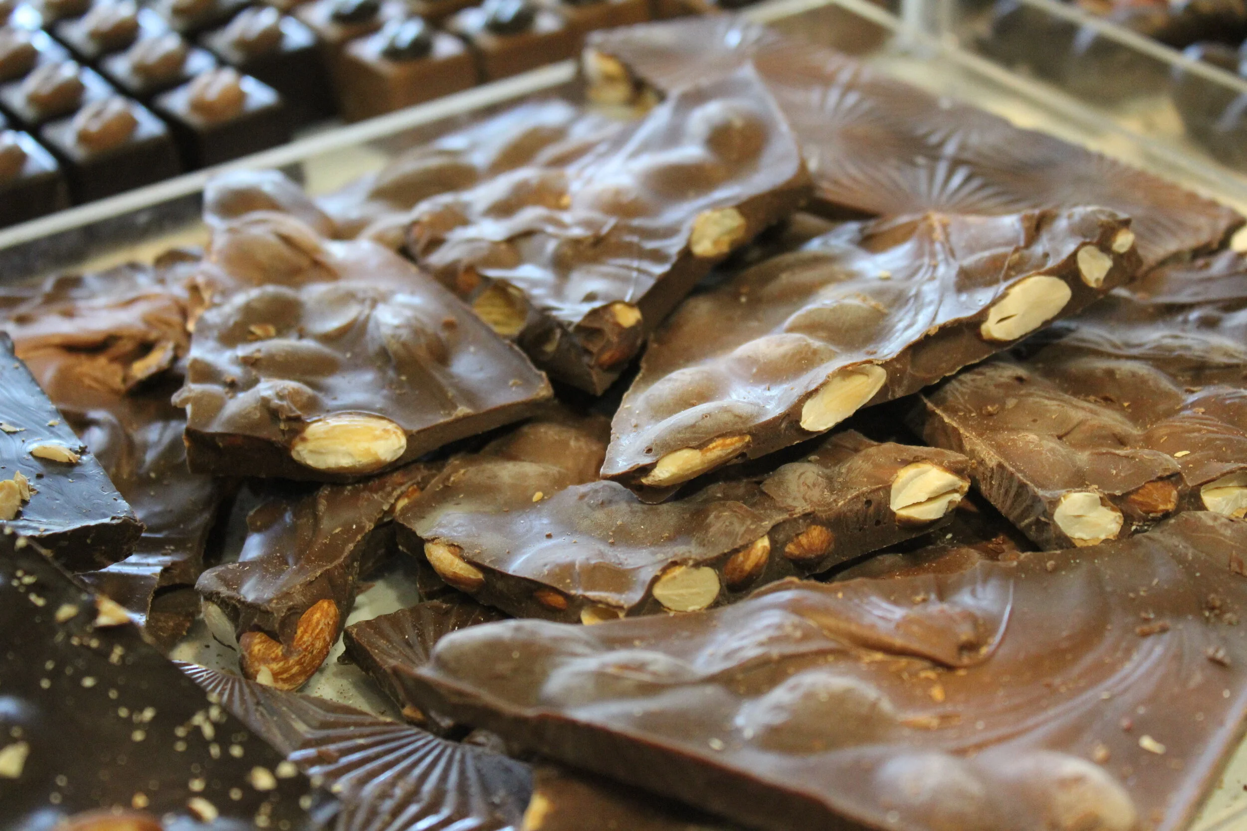 Various pieces of chocolate with nuts on a display tray.