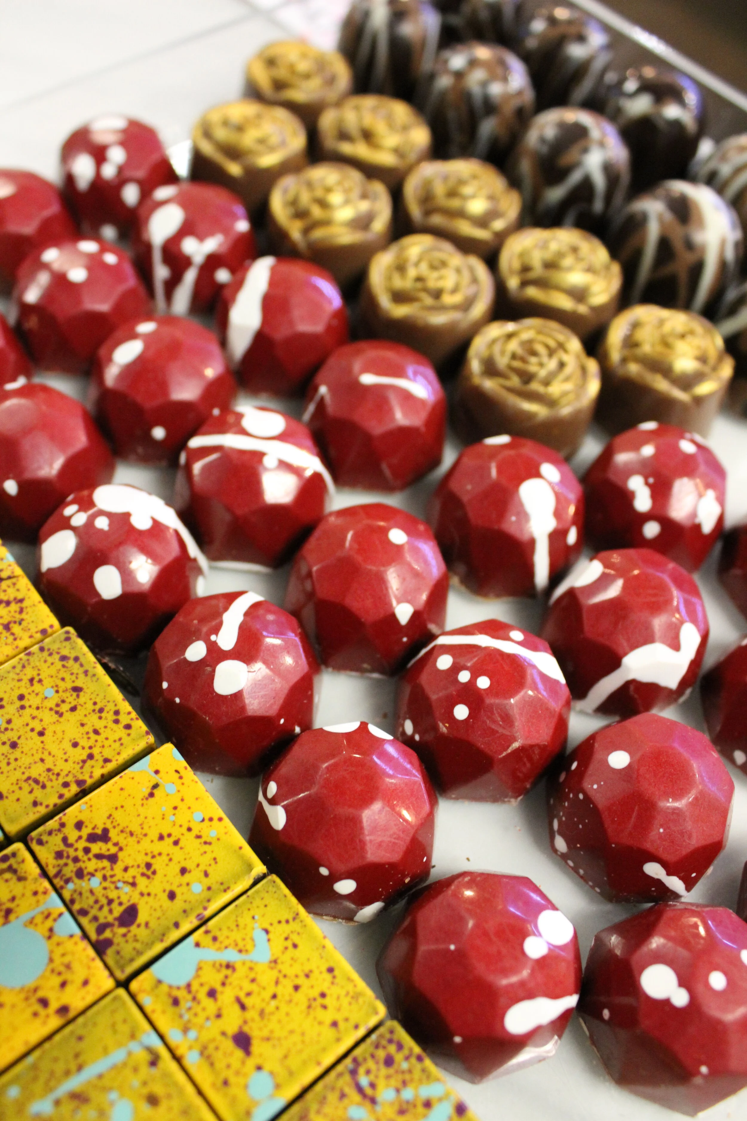 Various colorful, speckled chocolates with different designs are arranged on a white surface.