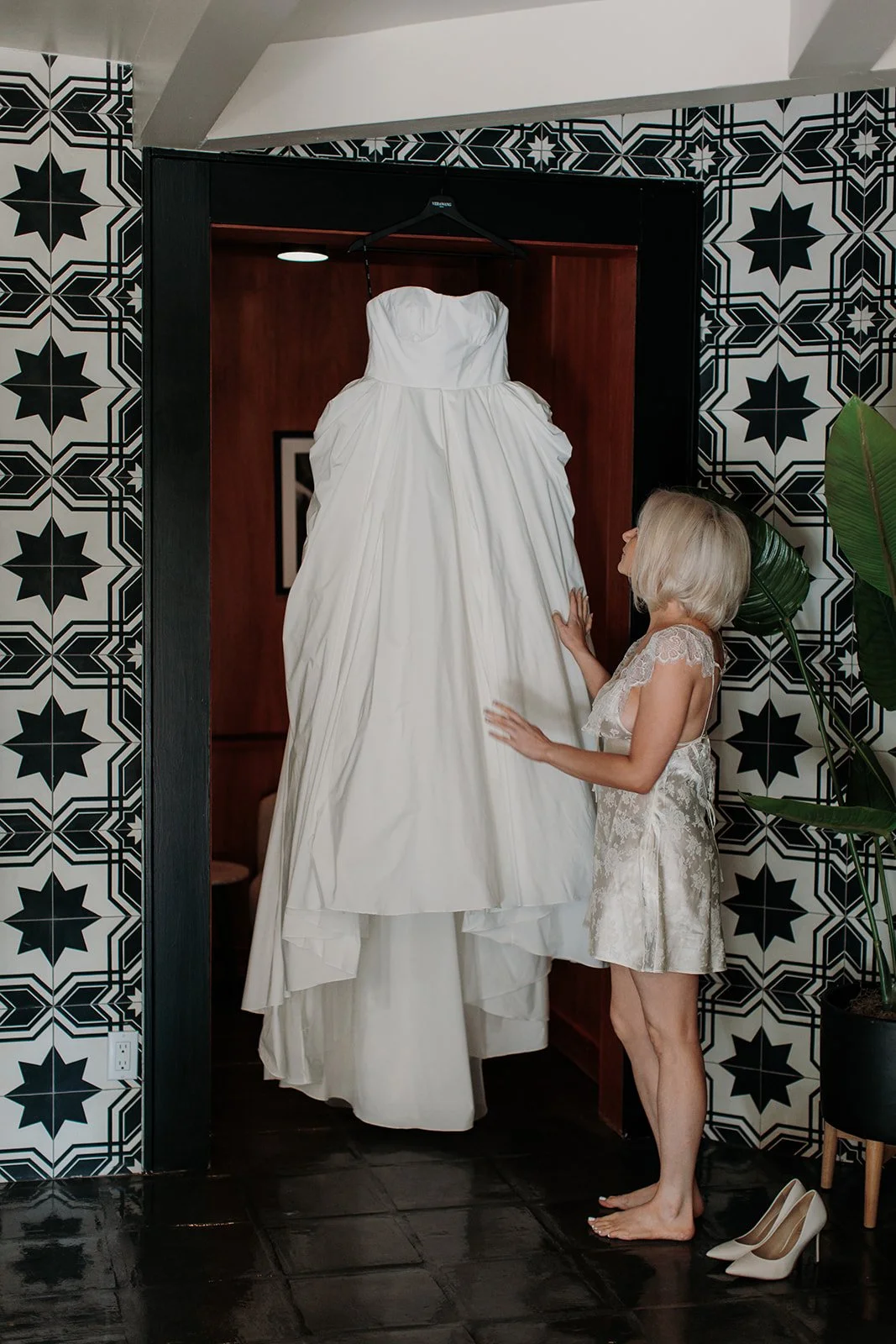 Bride adjusting her dress hanging on door
