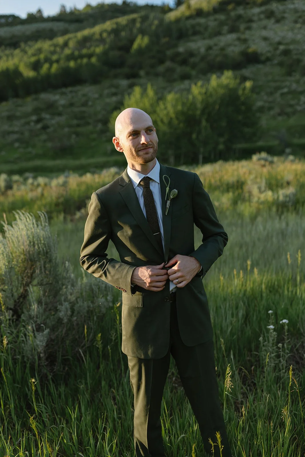Groom standing in field in suit