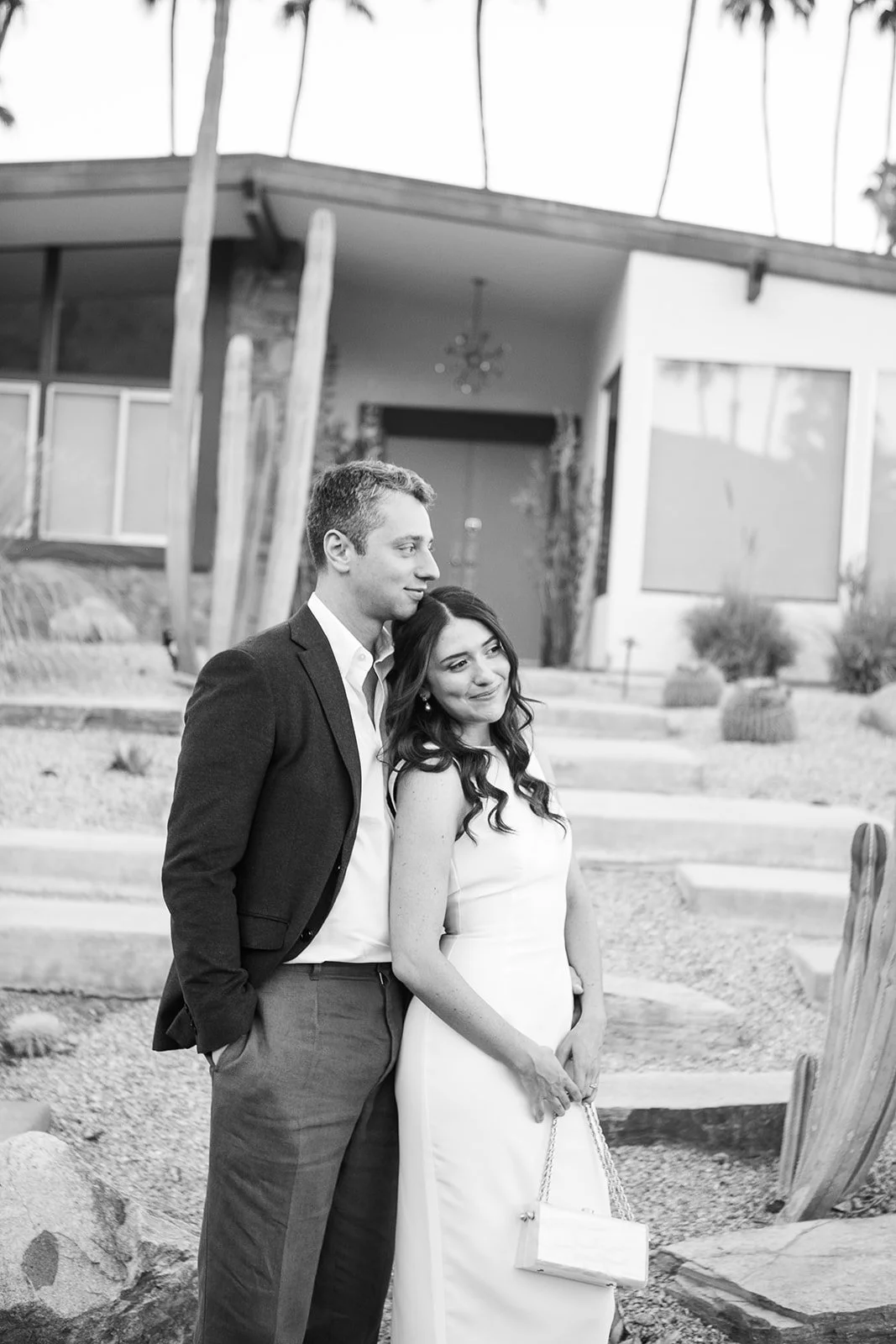 Bride and groom outside midcentury modern house embracing