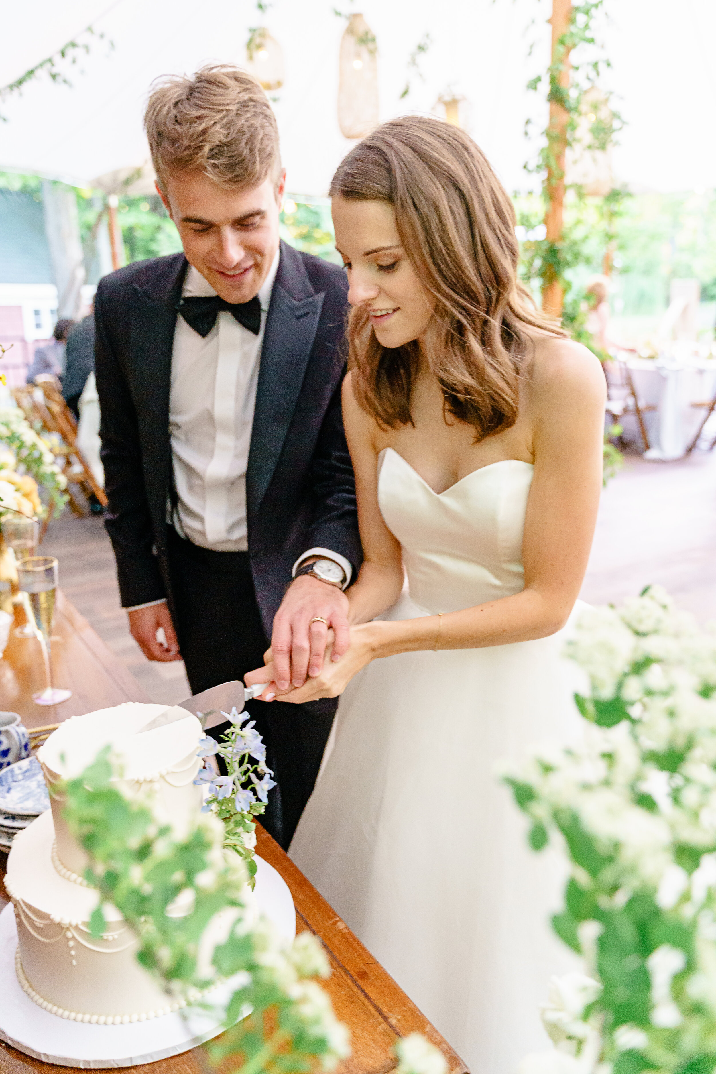 Elegant newly weds cutting the cake at their timeless outdoor summer wedding reception