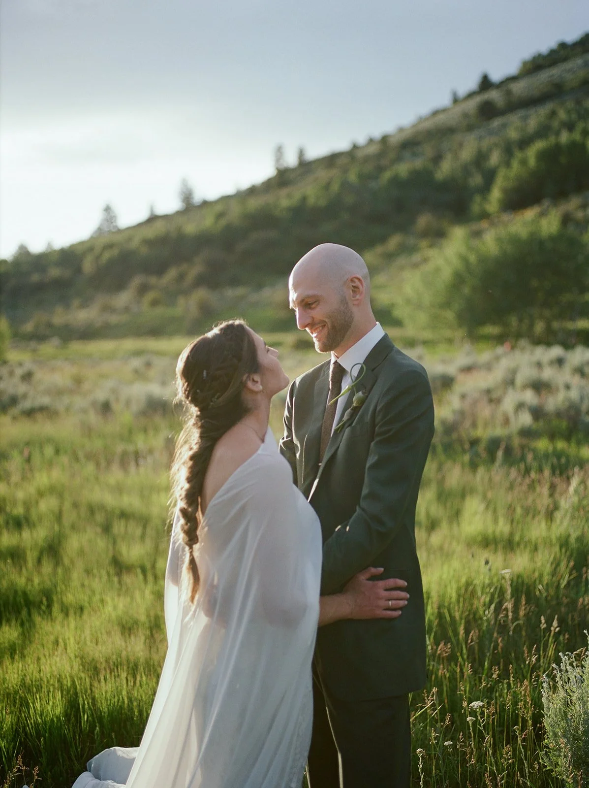 Bride looking up at groom with mountains behind