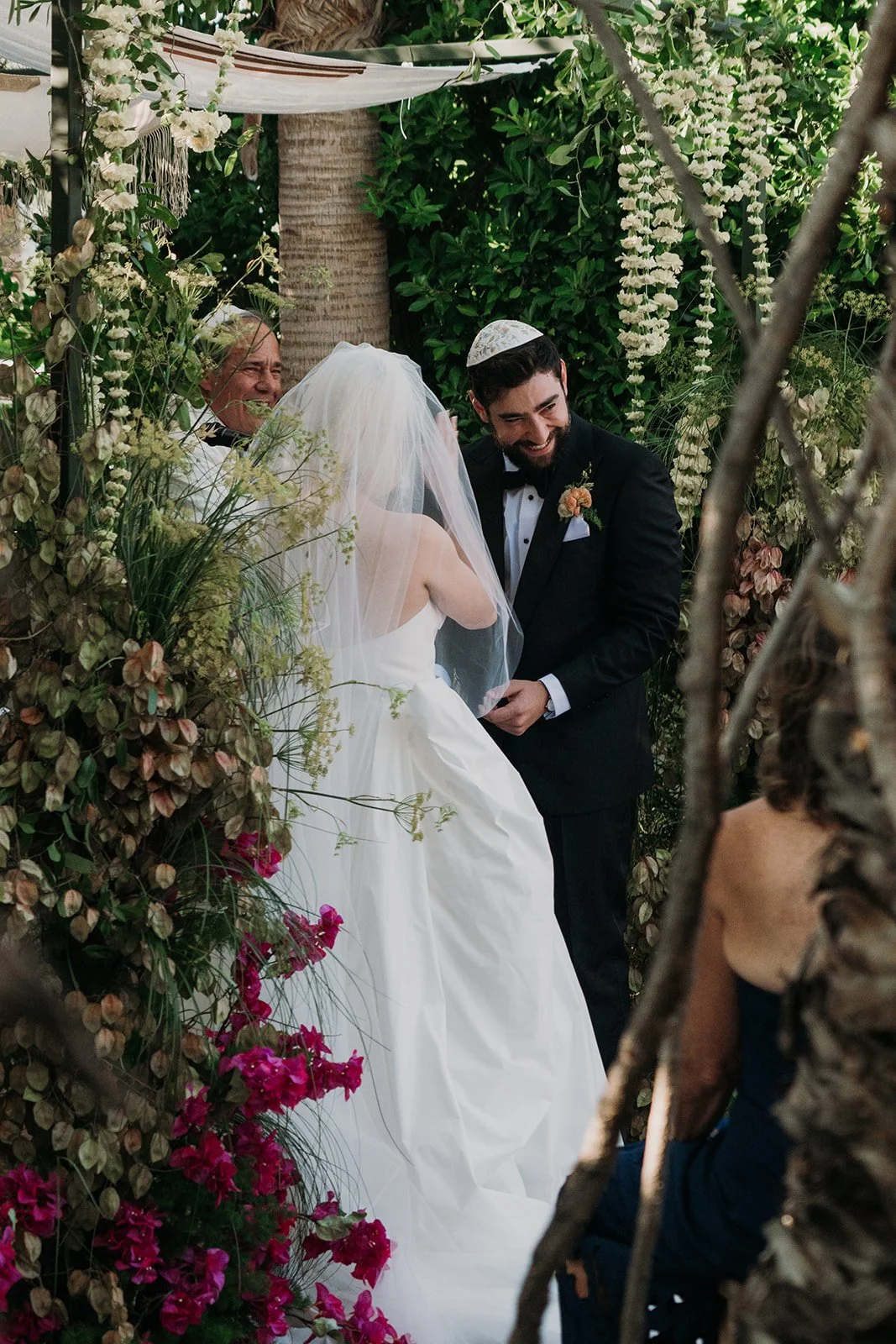 Groom smiling with bride under chuppah