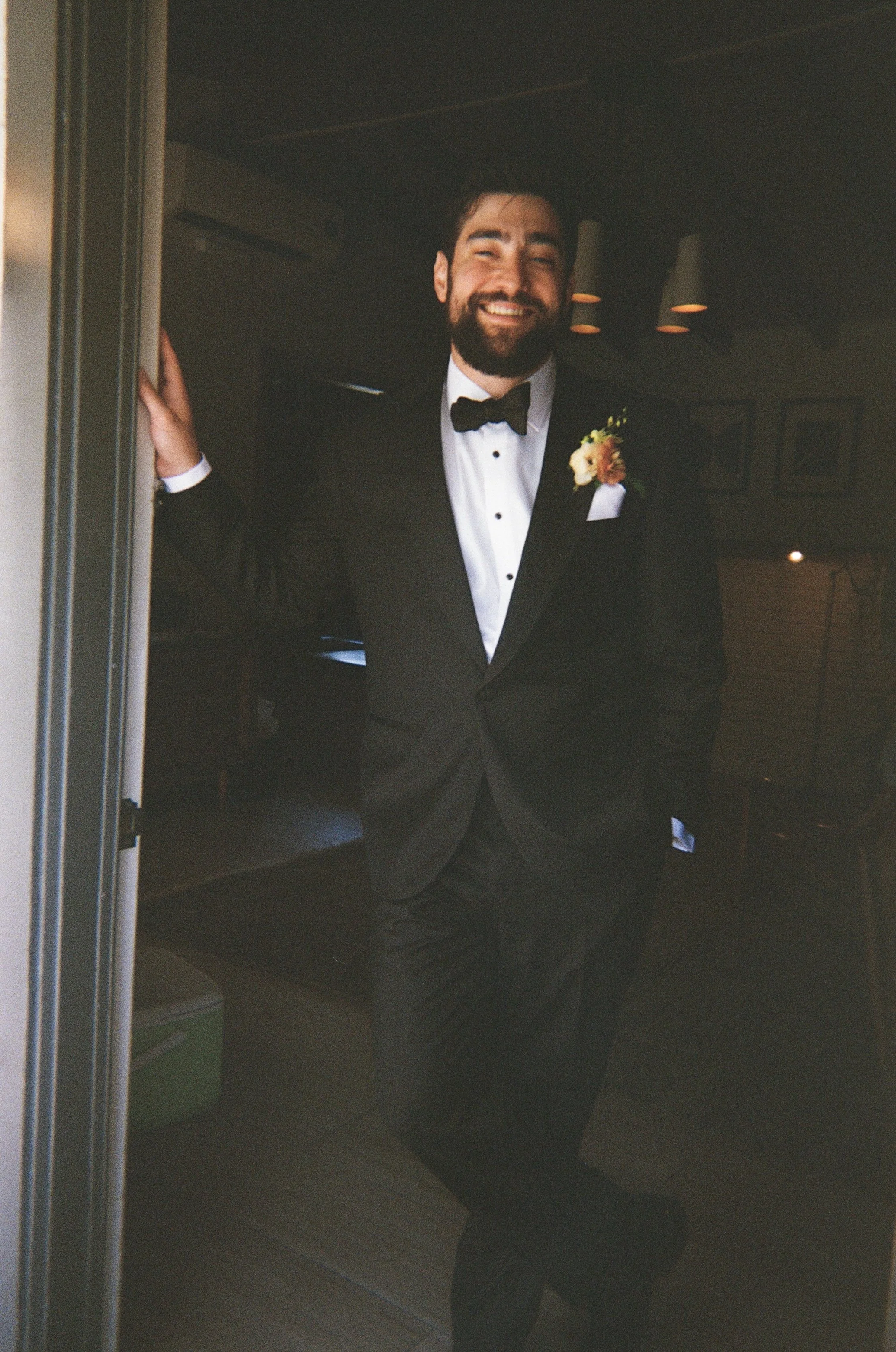 Groom standing in doorway with suit on