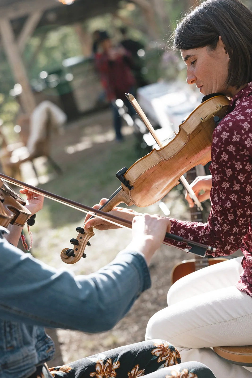 Two violinists playing outside with guests behind them