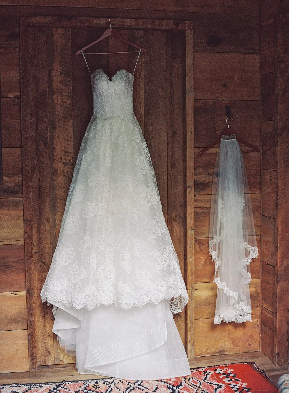 Wedding dress hanging in wooden cabin with veil hanging next to it