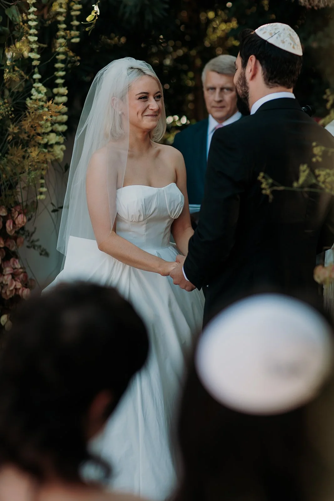 Bride and groom holding hands under chuppah