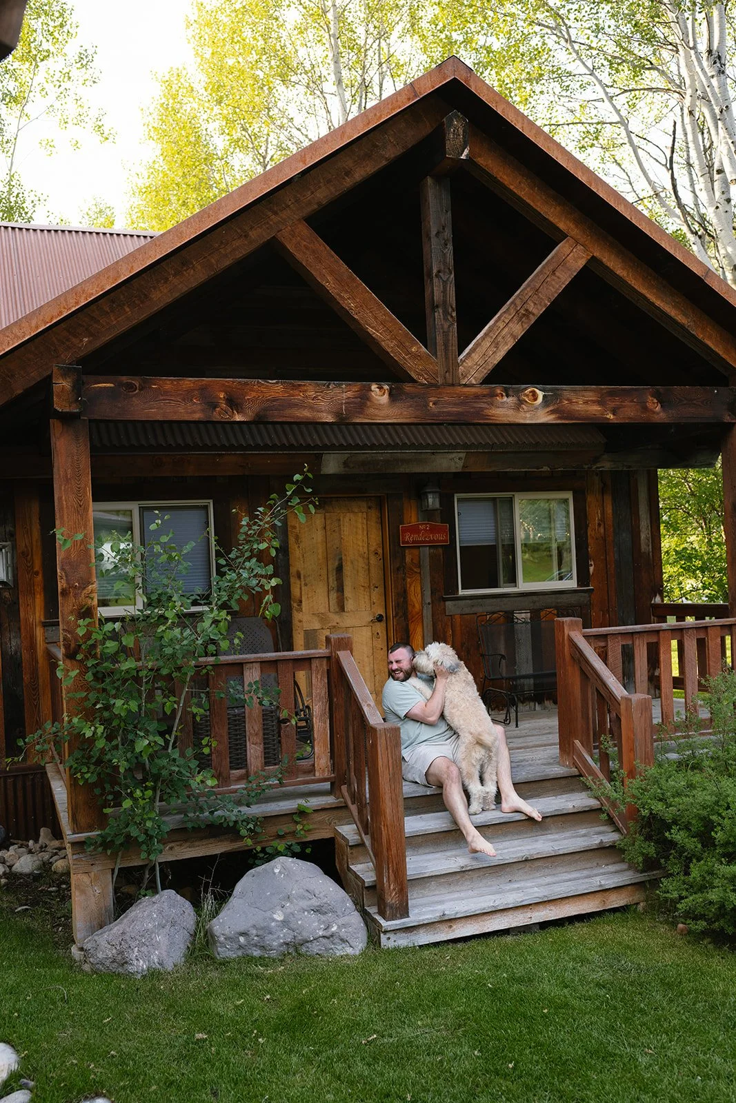Wedding guest sitting on cabin stairs petting dog