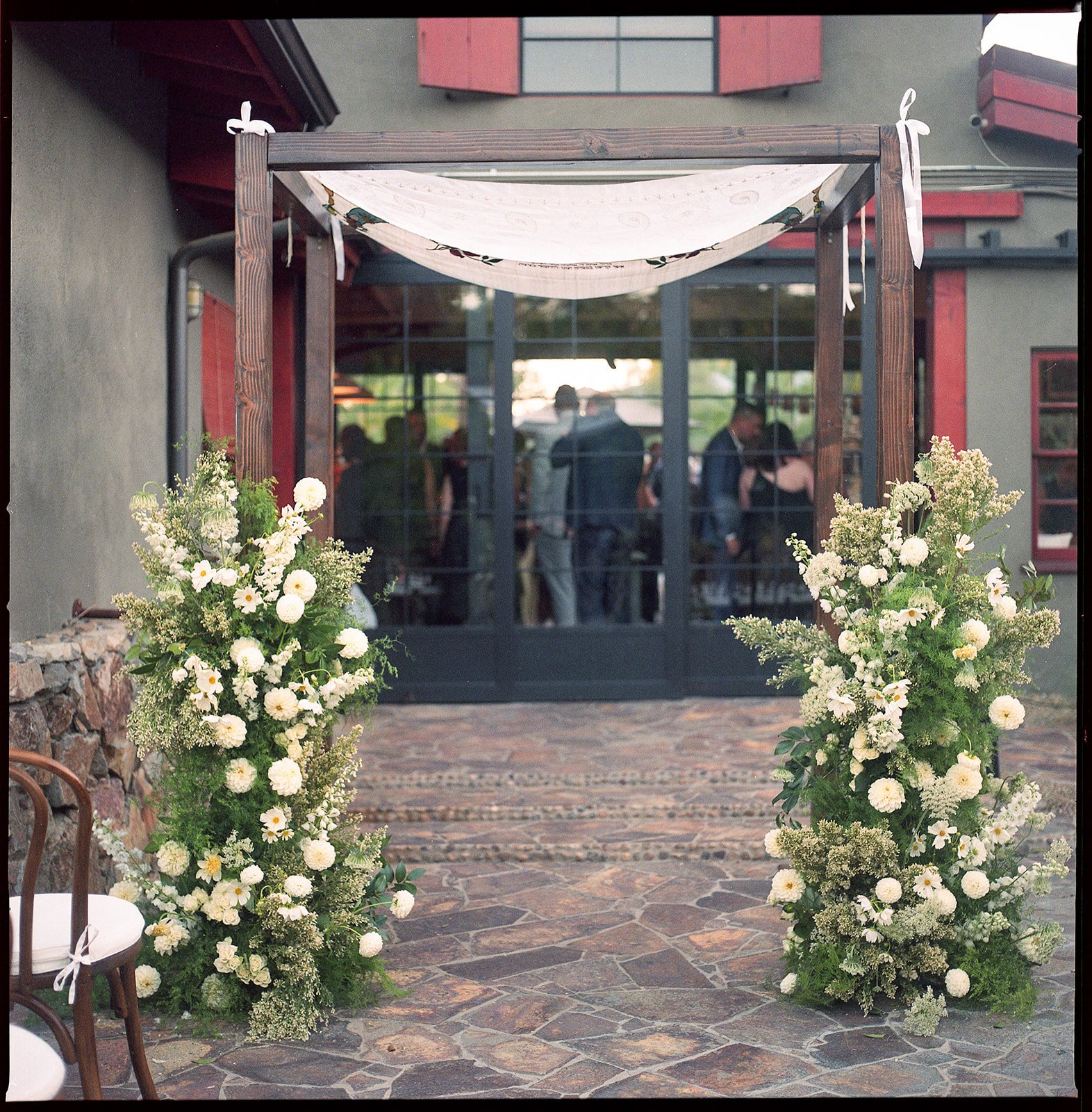 Chuppah with wedding guests in barn behind it