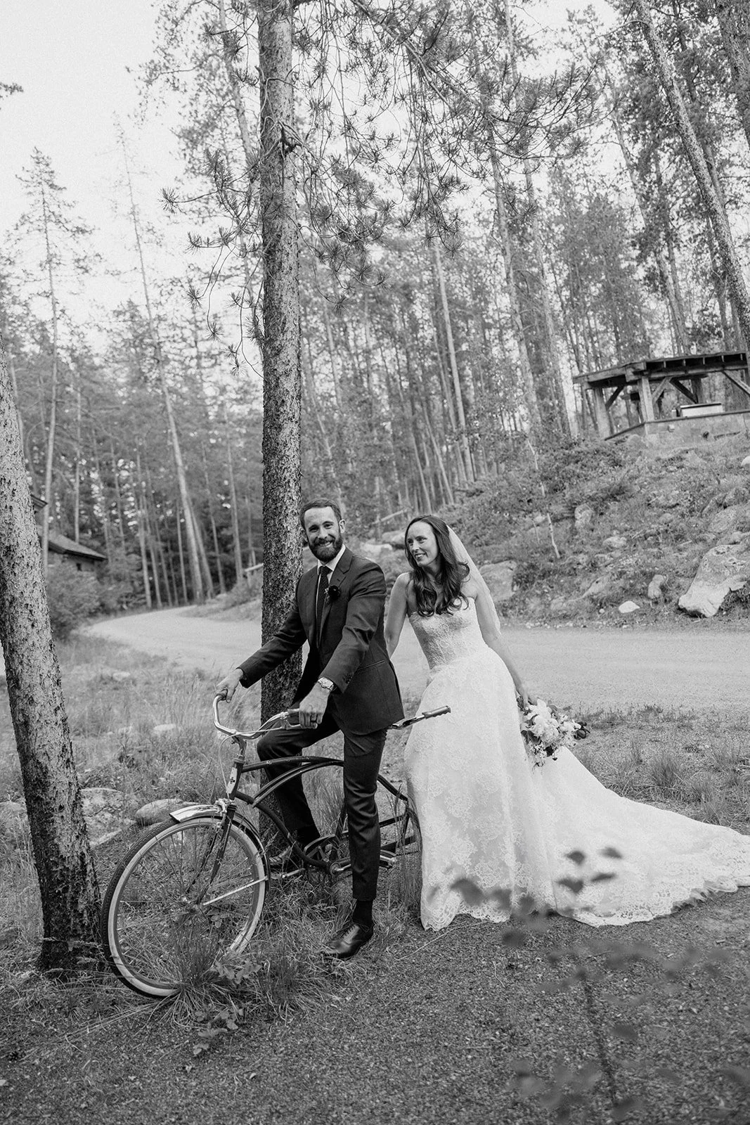 Bride and groom getting onto tandem bike in black and white