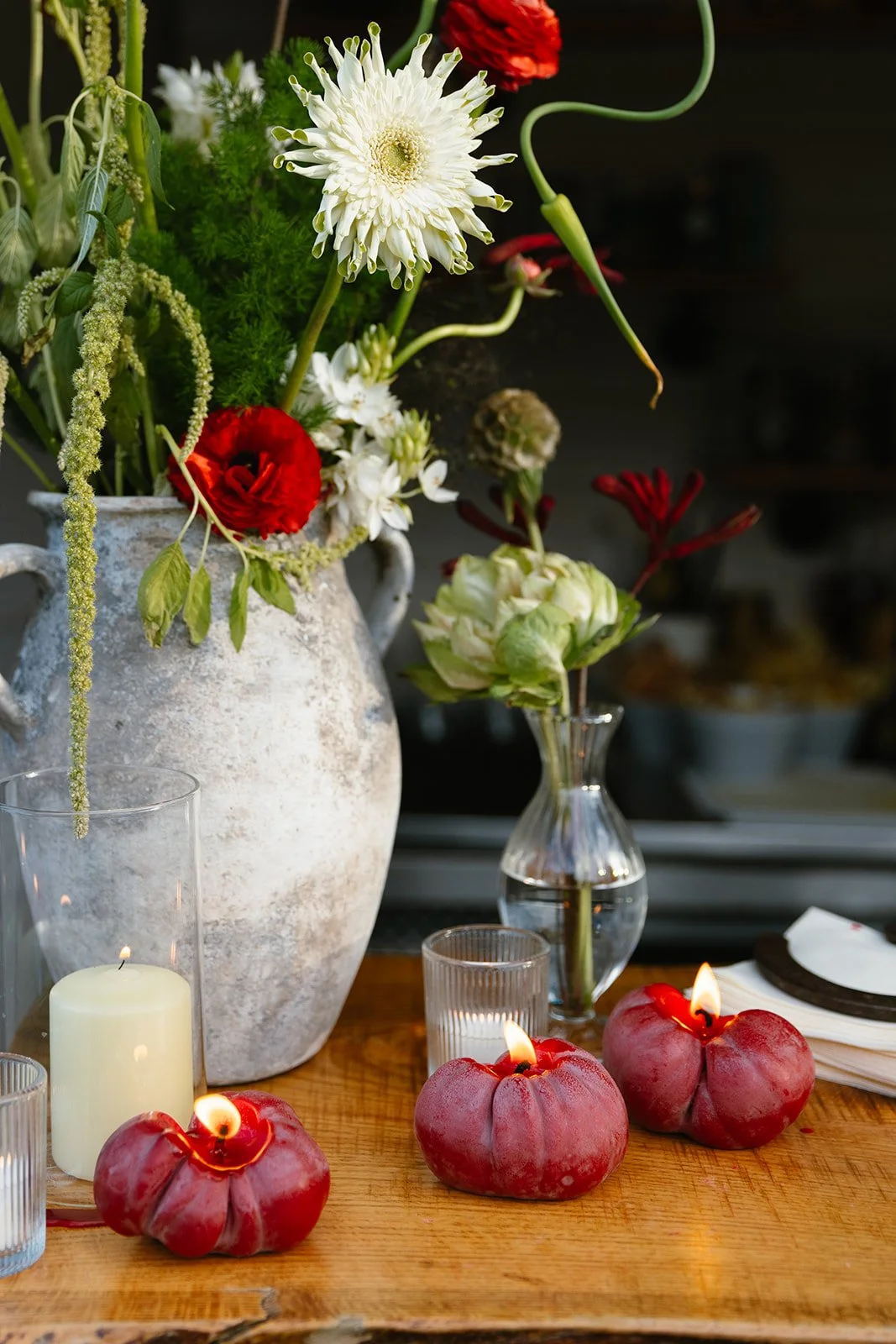 Red, white and green floral arrangement with candles lit around it
