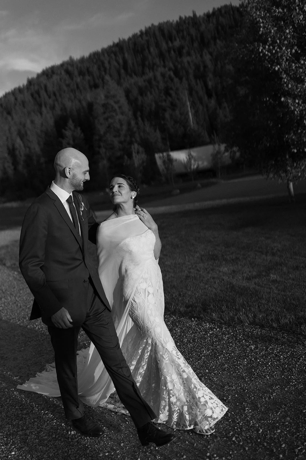 Bride and groom arm in arm walking by mountains