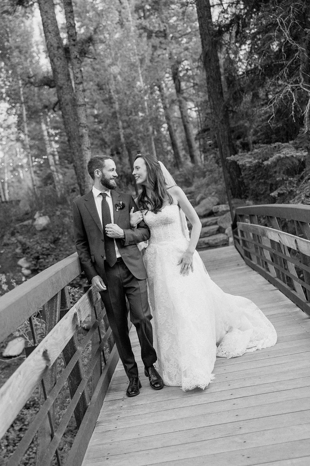 Bride and groom arm in arm walking across bridge outside