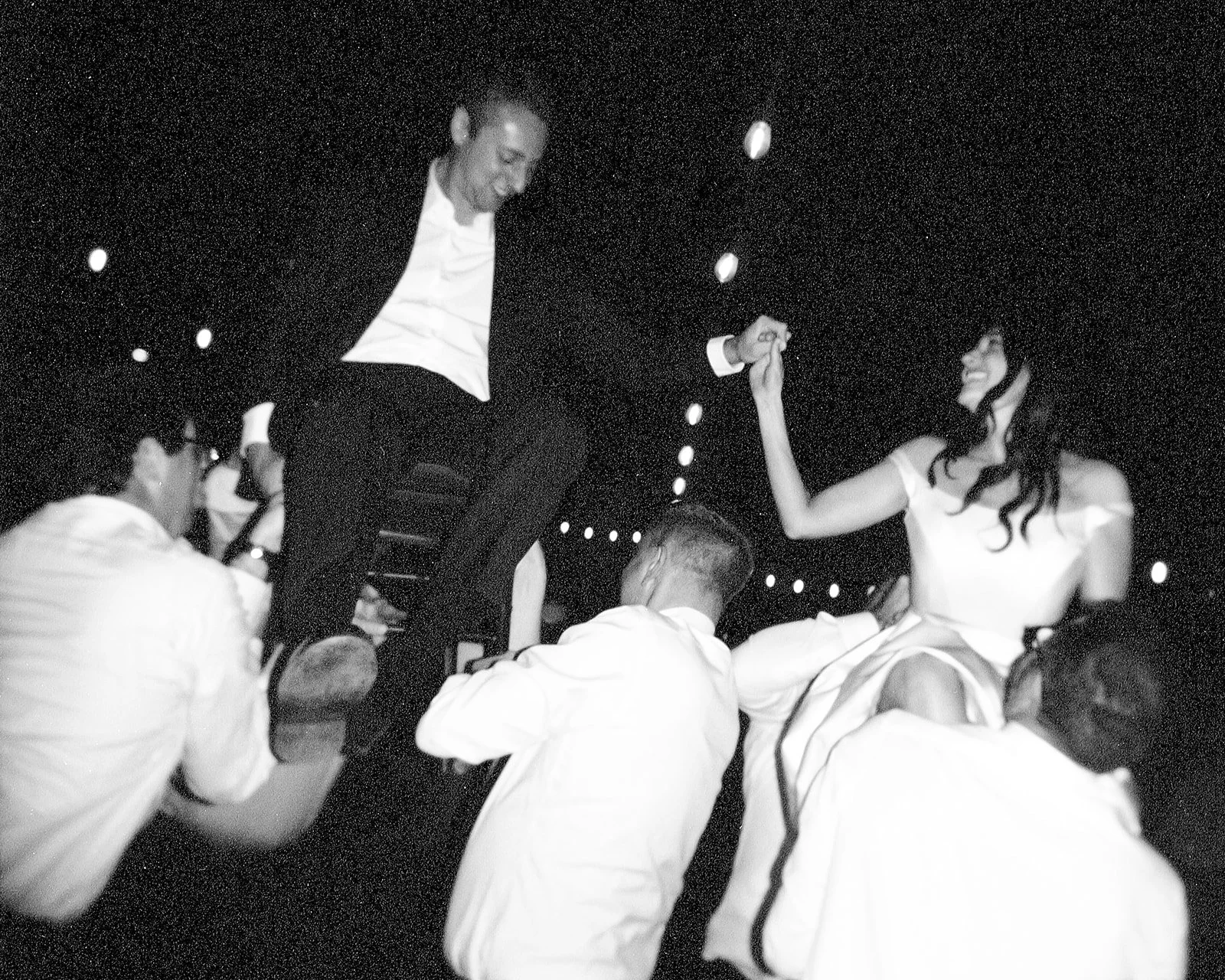 Bride and groom being lifted on hora