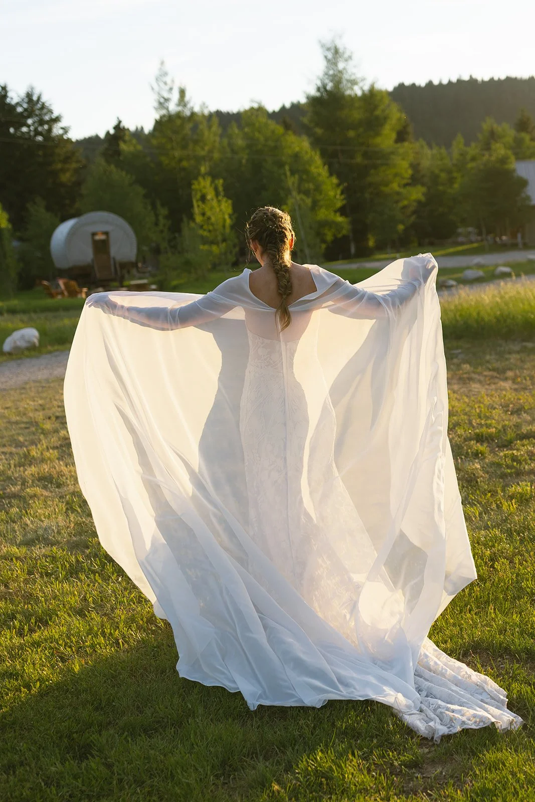 Bride with arms out showing dress in field