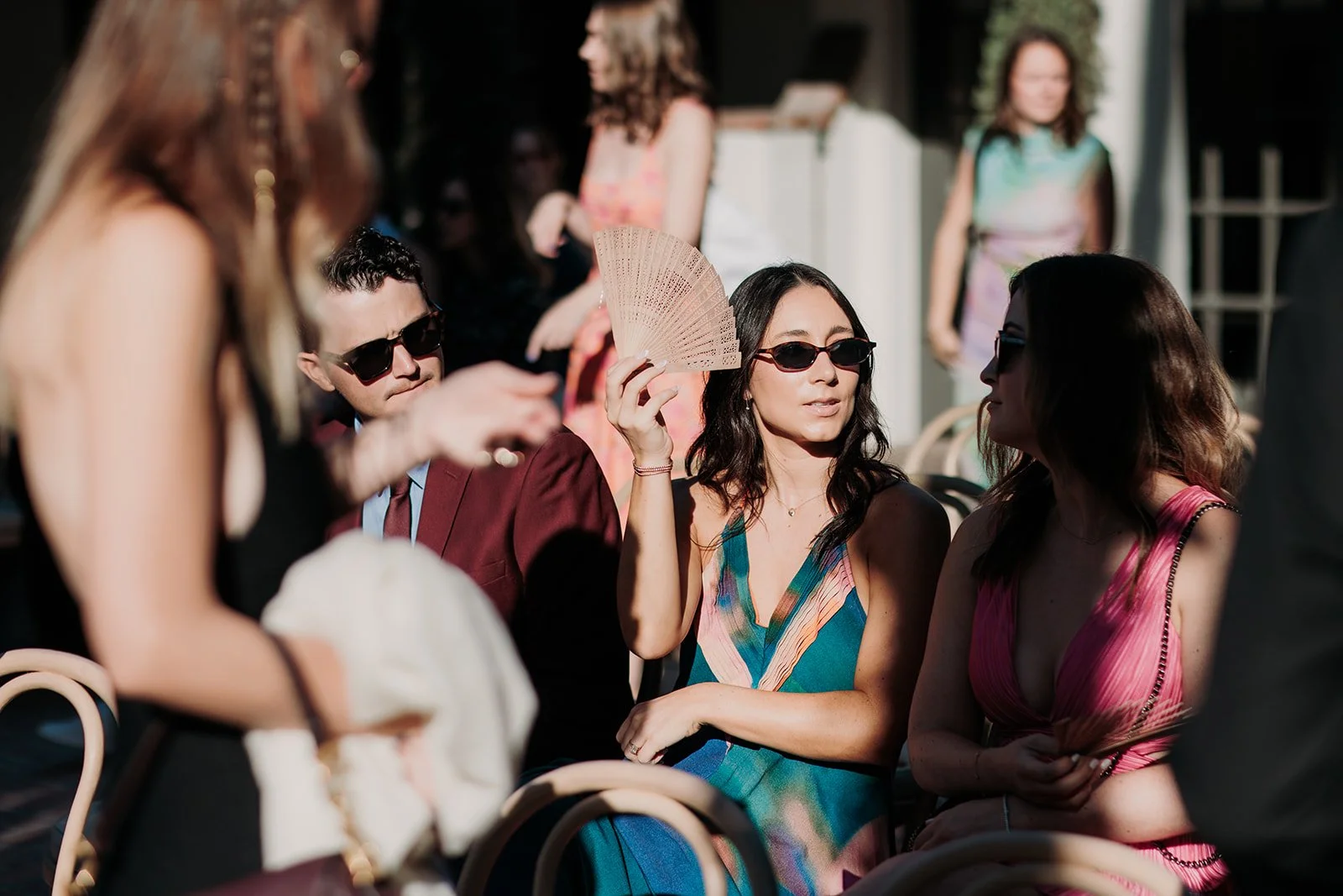 Guests using custom fans at wedding ceremony