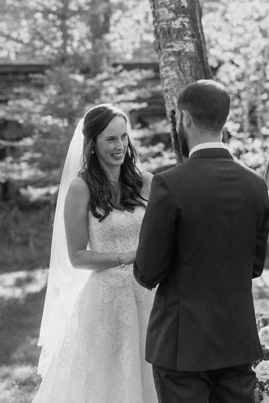 Bride smiling at groom and holding hands at wedding ceremony