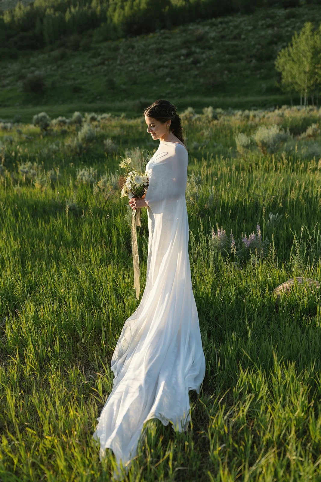 Bride standing with bouquet in field