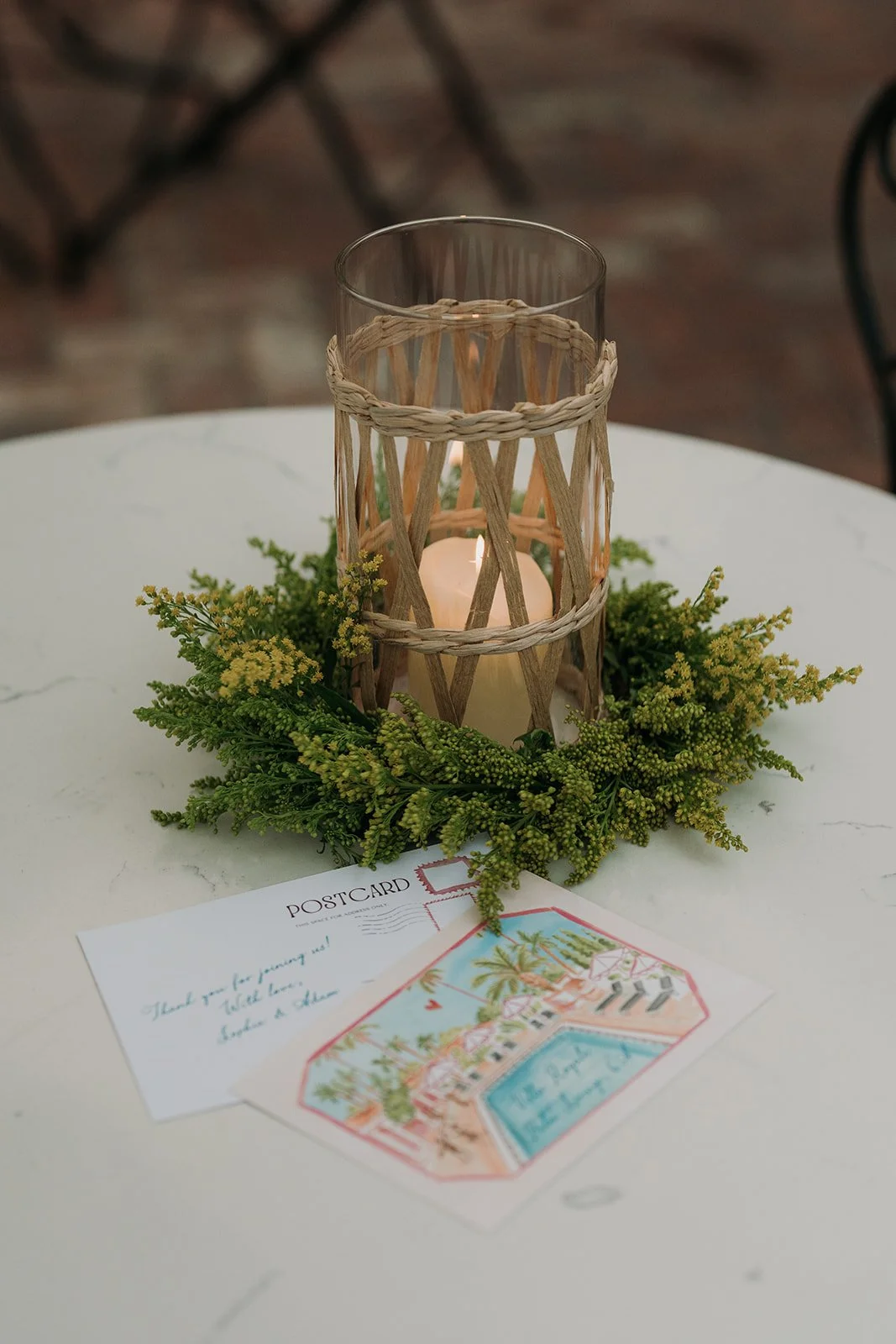 Flower and candle arrangement with postcards on table