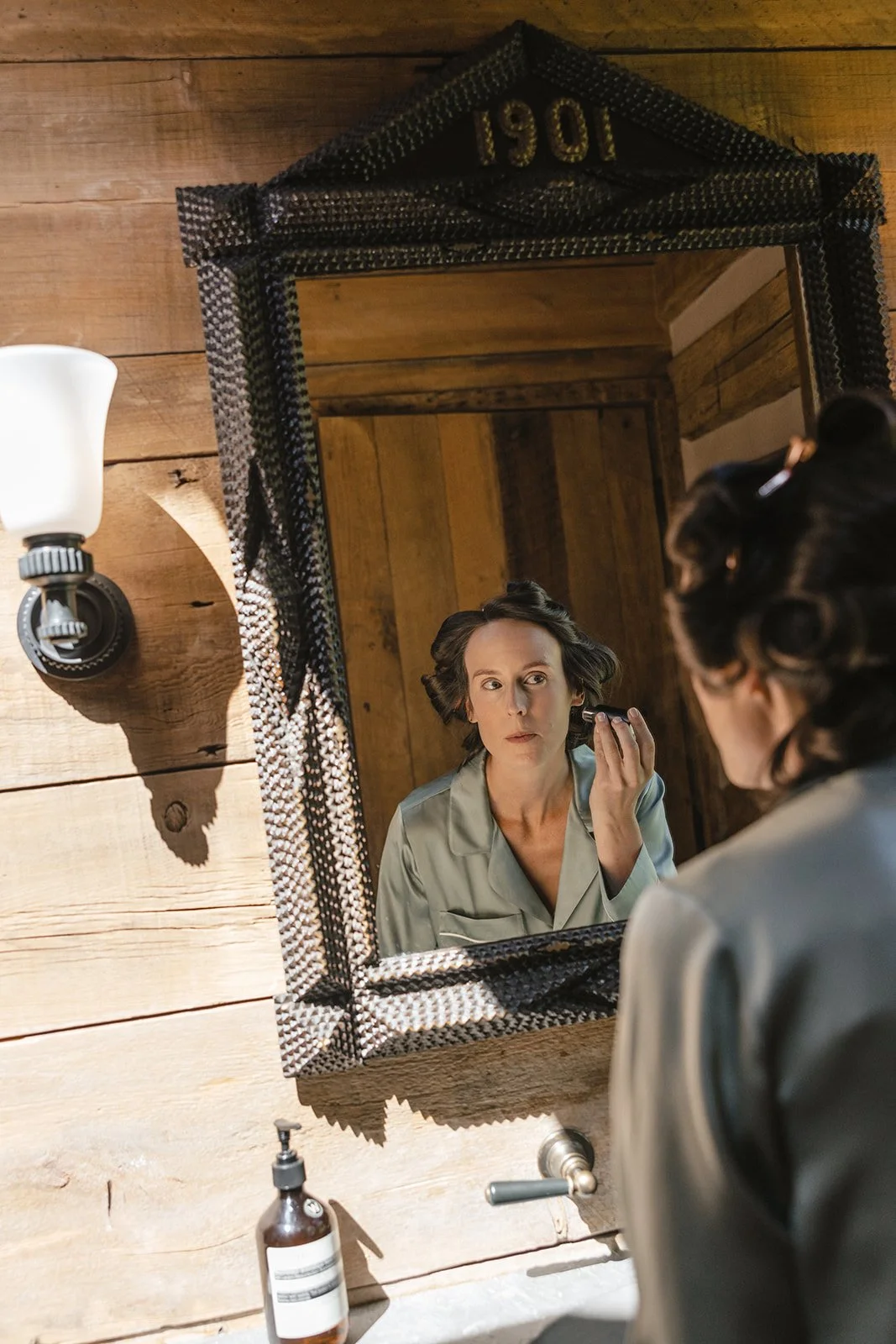 Bride in pajamas putting makeup on in the mirror