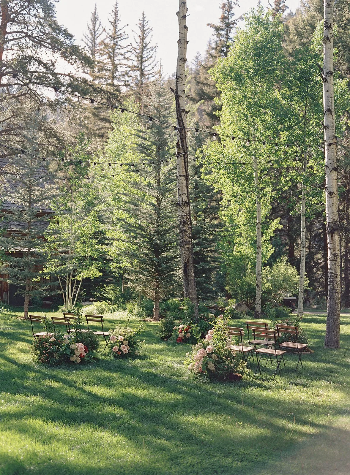 Ceremony seats outside in tree grove with florals all around