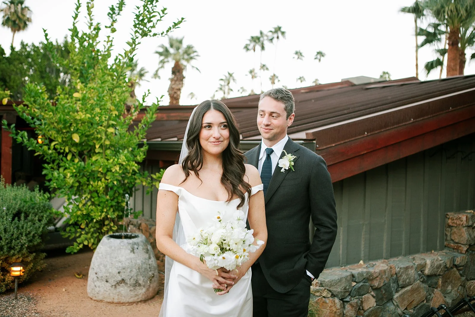 Bride with her veil and flowers and groom behind her