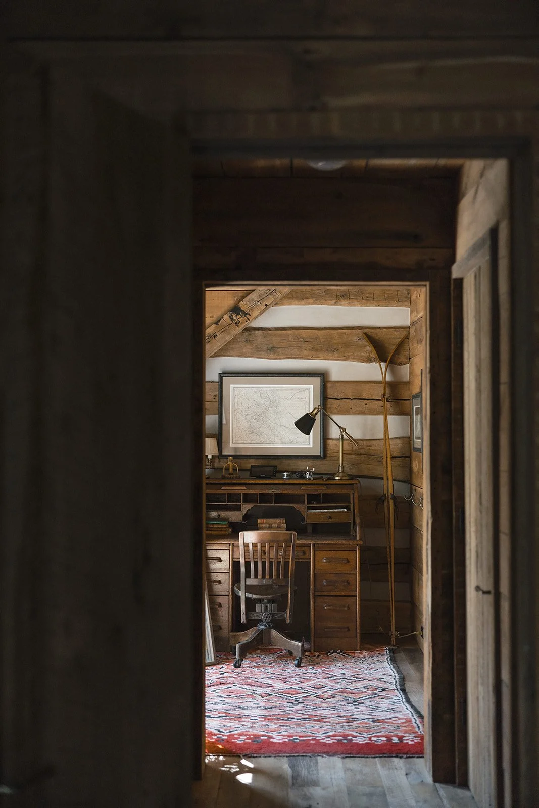 Wooden rolltop desk with wooden chair in corner of cabin