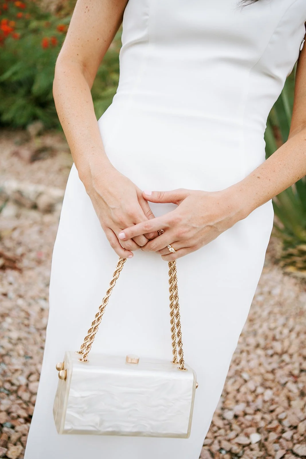 Bride holding gold chain purse with white dress