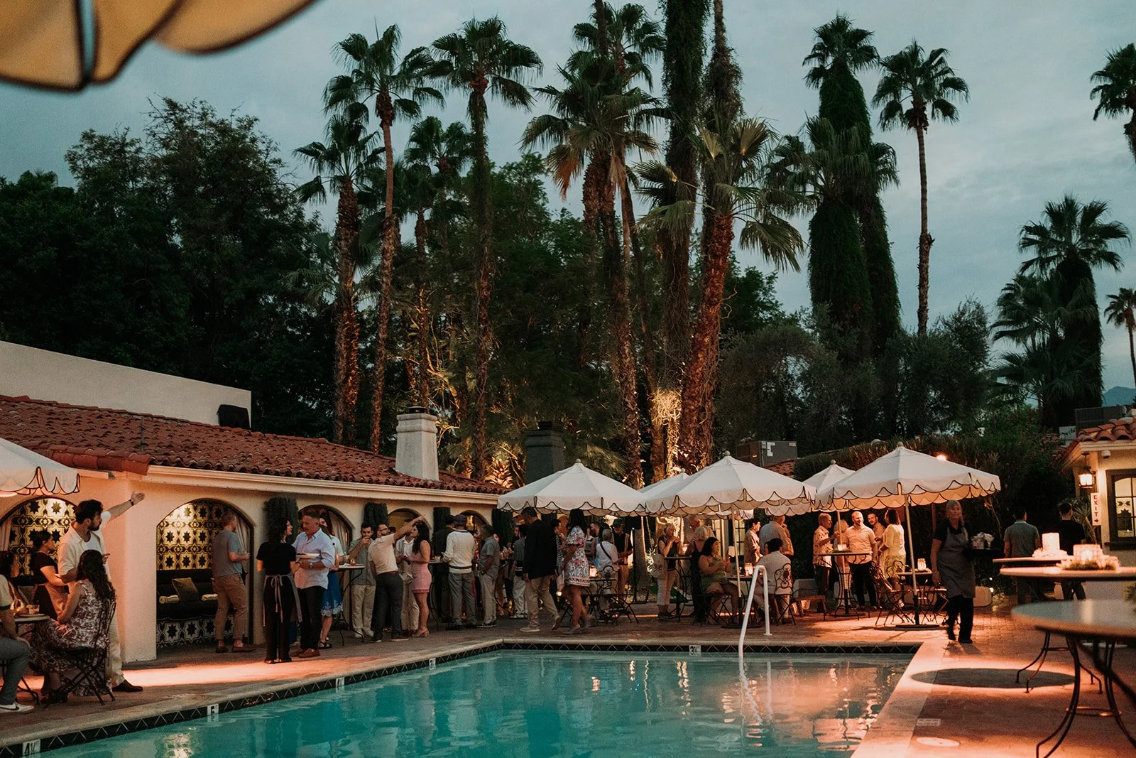 Welcome party guests gathered around the pool at dusk