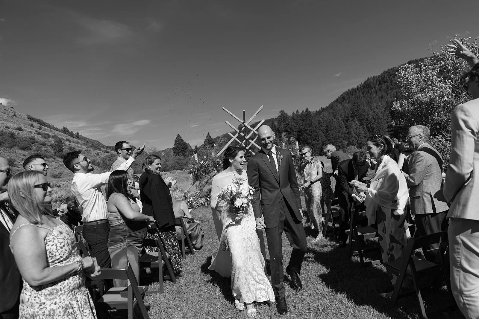 Bride and groom walking down aisle with guests all around