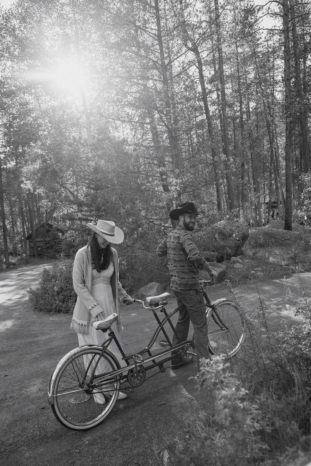 Bride and groom preparing to get onto tandem bike, both smiling