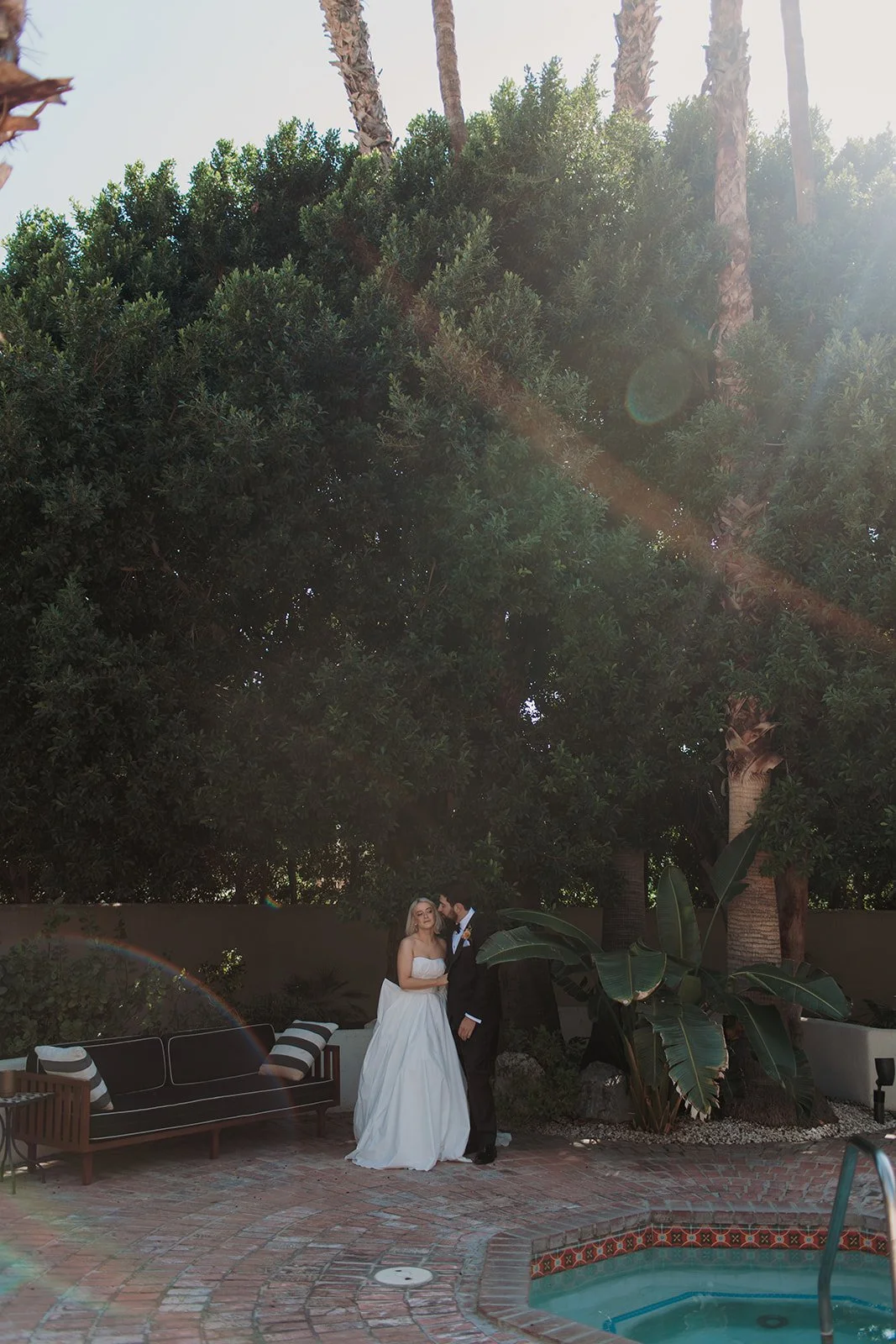 Bride and groom in trees by the pool kissing