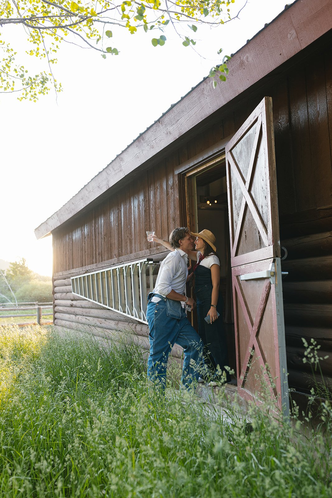 Couple leaning in for kiss outside of barn