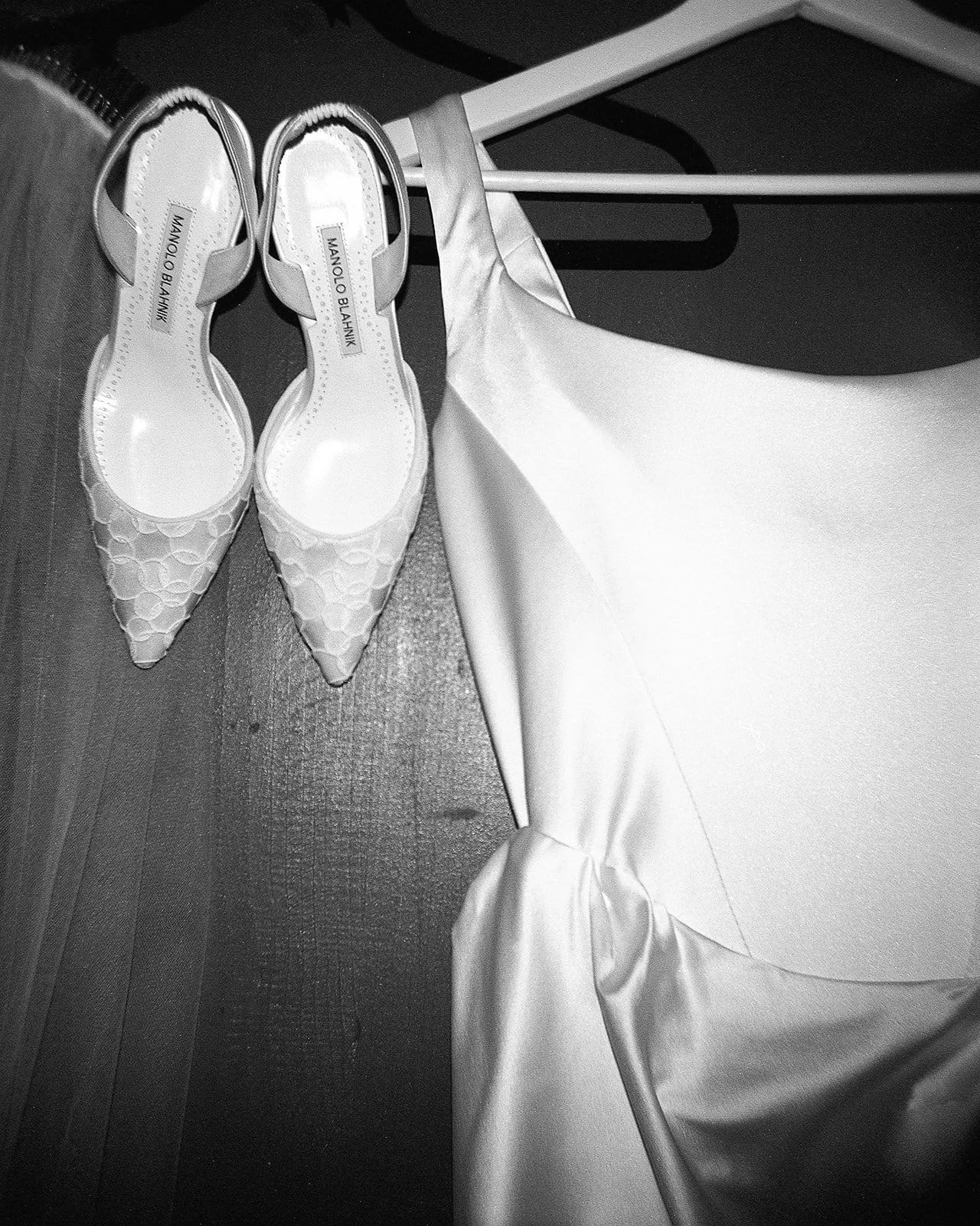 Close up of wedding dress with shoes hanging next to it