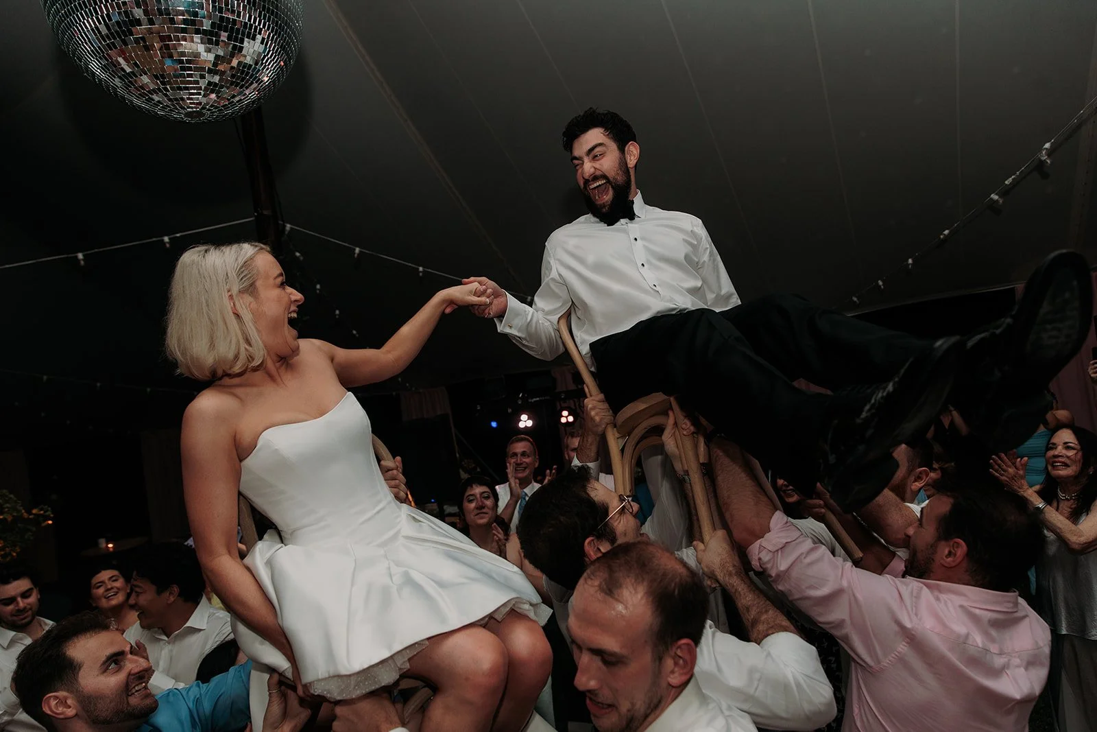 Bride and groom being raised in hora celebration