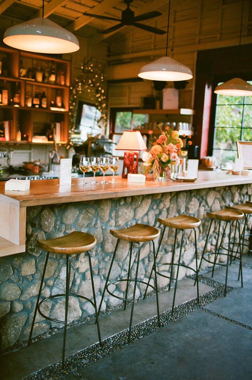 Bar inside barn with wine glasses and floral arrangements