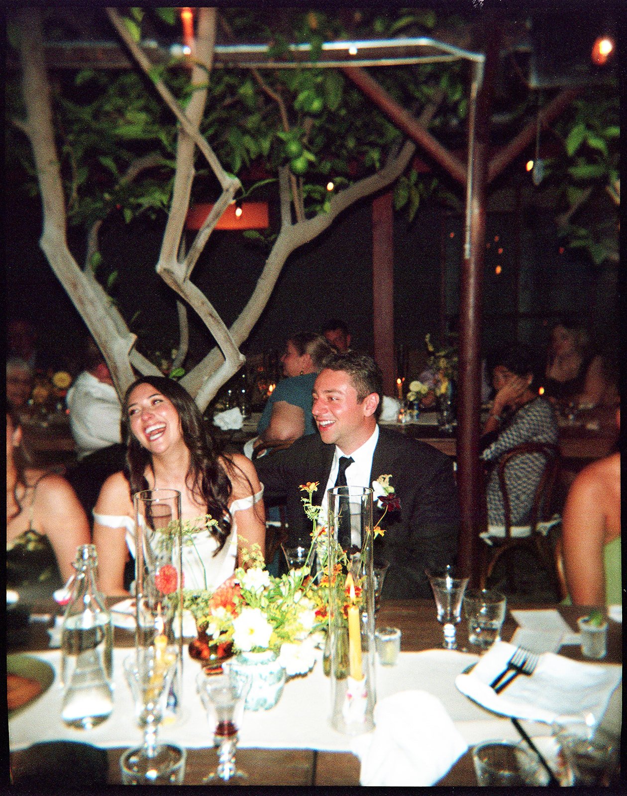 Bride and groom sitting at dinner table laughing