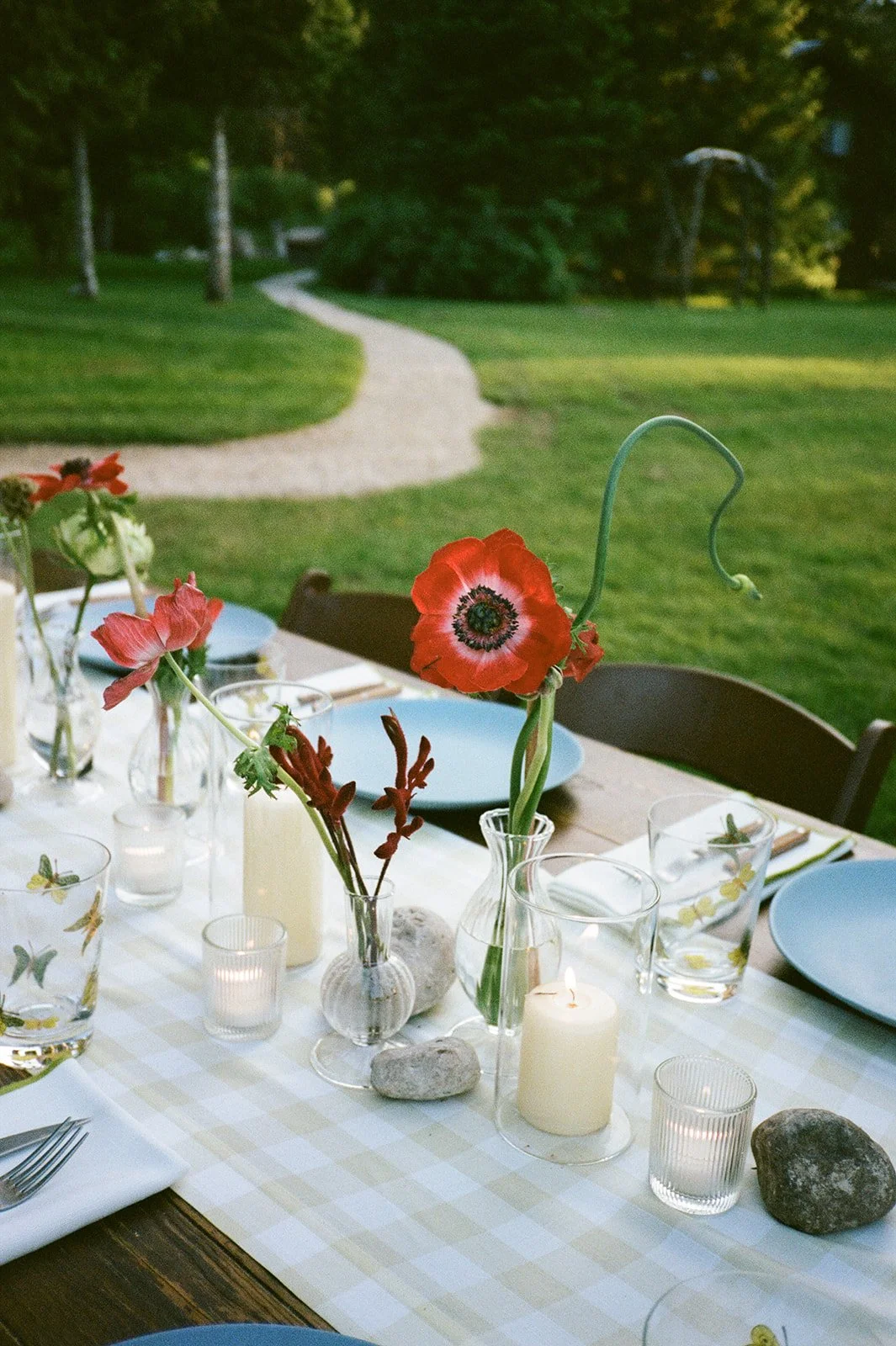 Table with red floral arrangement set for dinner outside