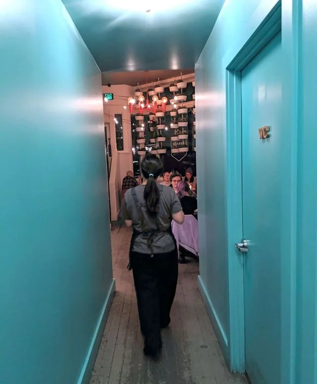 This is Tiff walking through the hallway at @thegeraldseattle. It was a walk that our servers and cooks took dozens of times during our pop up dinners, delivering food to hungry folks. Also happens to cross the restrooms, so this was a HIGH TRAFFIC a